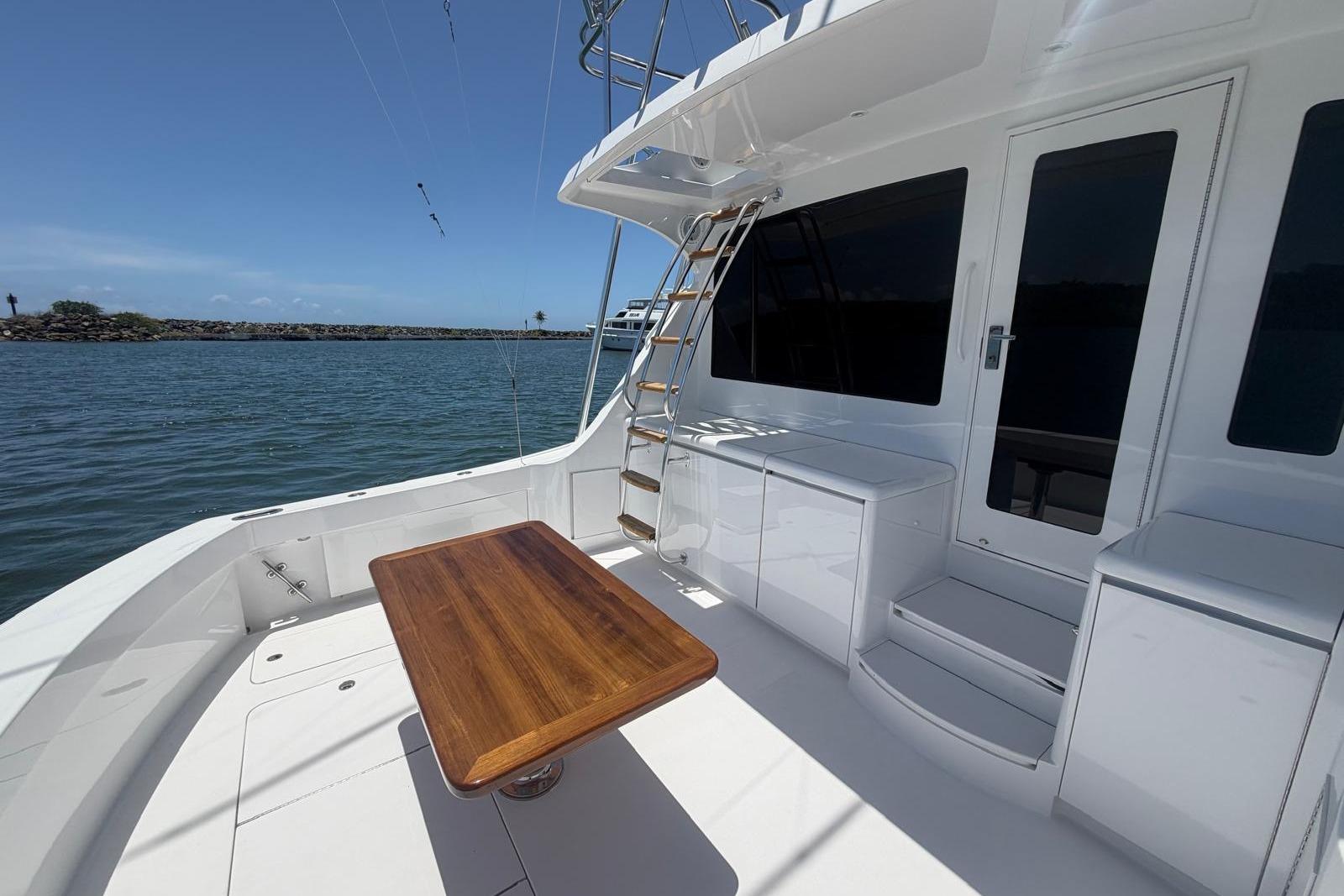 2003 Hatteras 54 Convertible yacht deck with wooden table and ocean view.