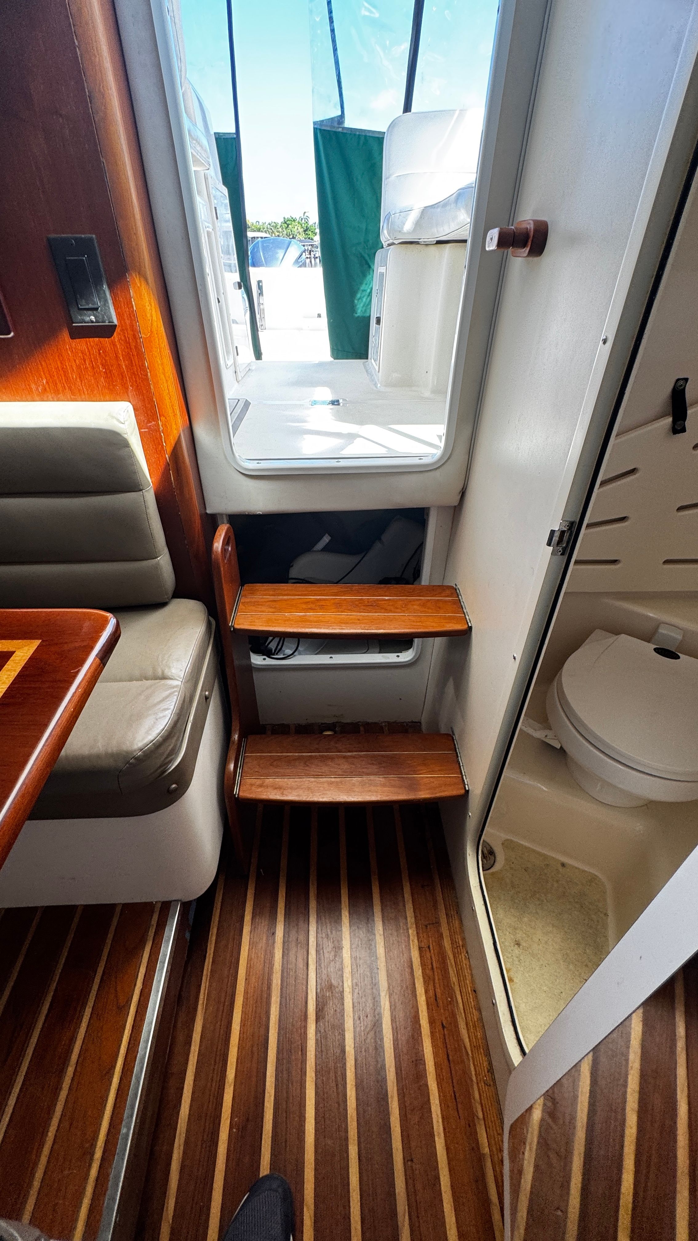 Interior of a 2003 Pursuit 3070 with wood flooring, seating, and access to the toilet.