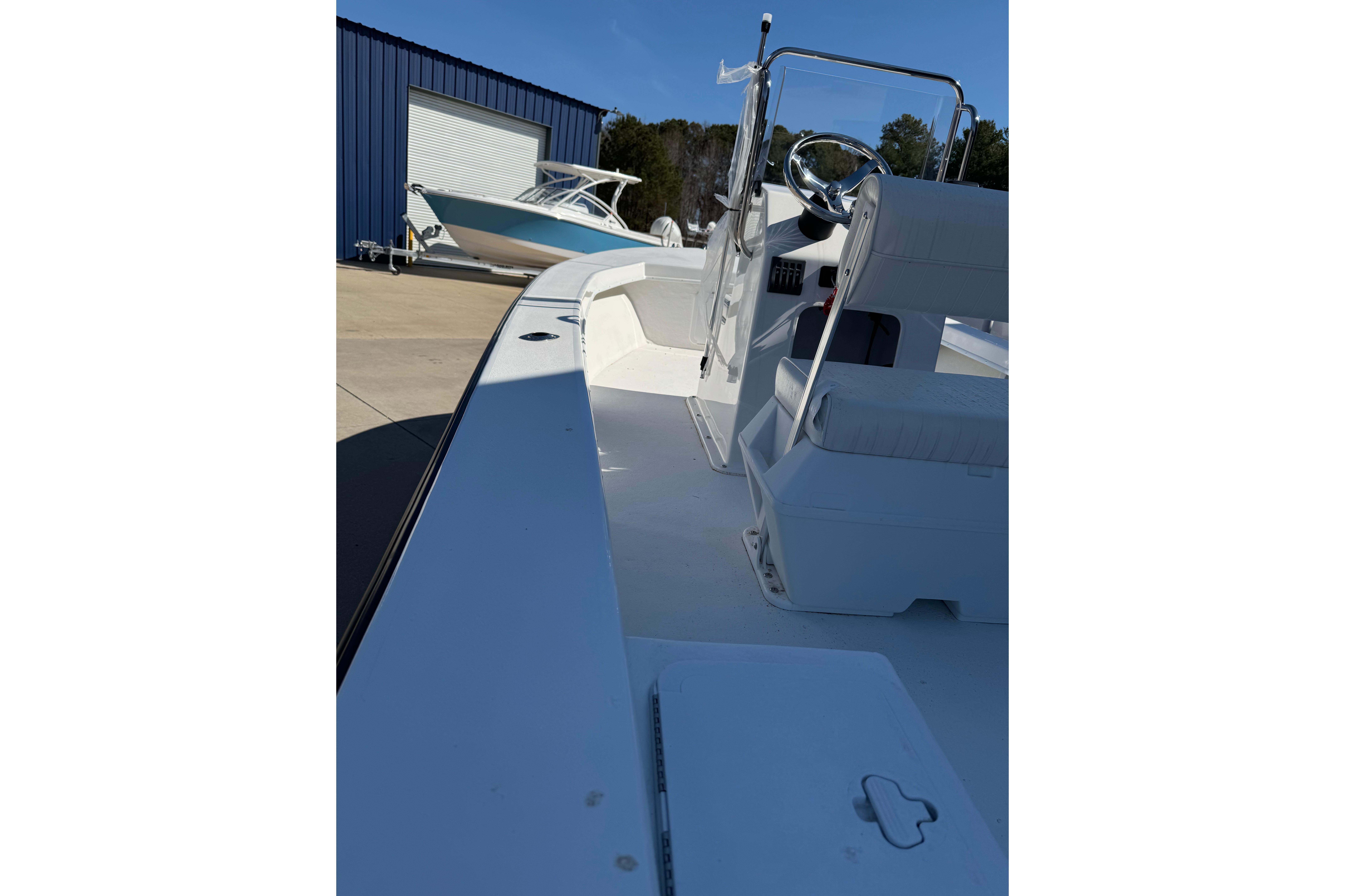2026 C-Hawk 18 Center Console boat, white interior, parked near blue building.