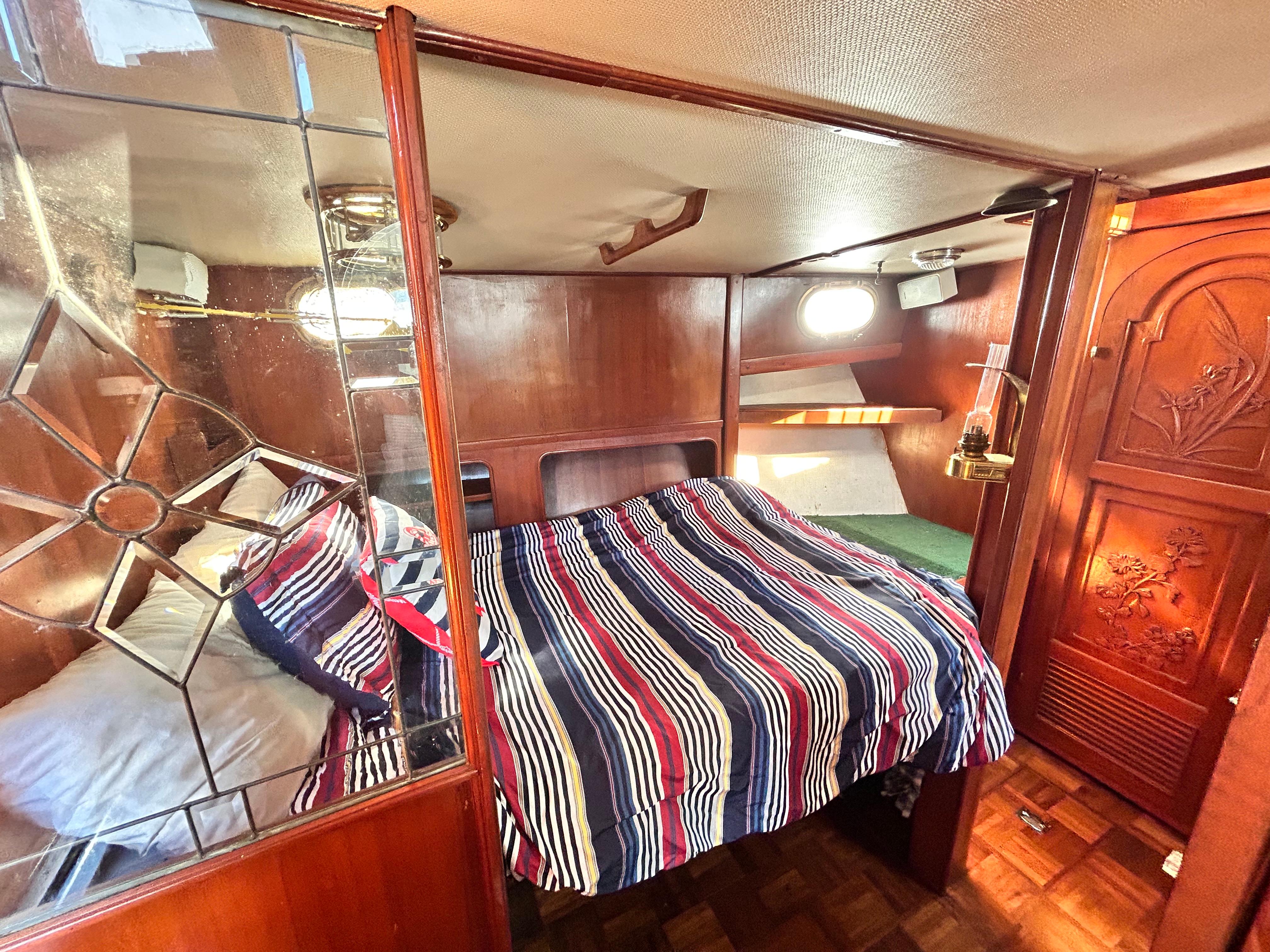 Cozy cabin interior of 1989 Albin 43 Trawler with striped bedding and wood paneling.
