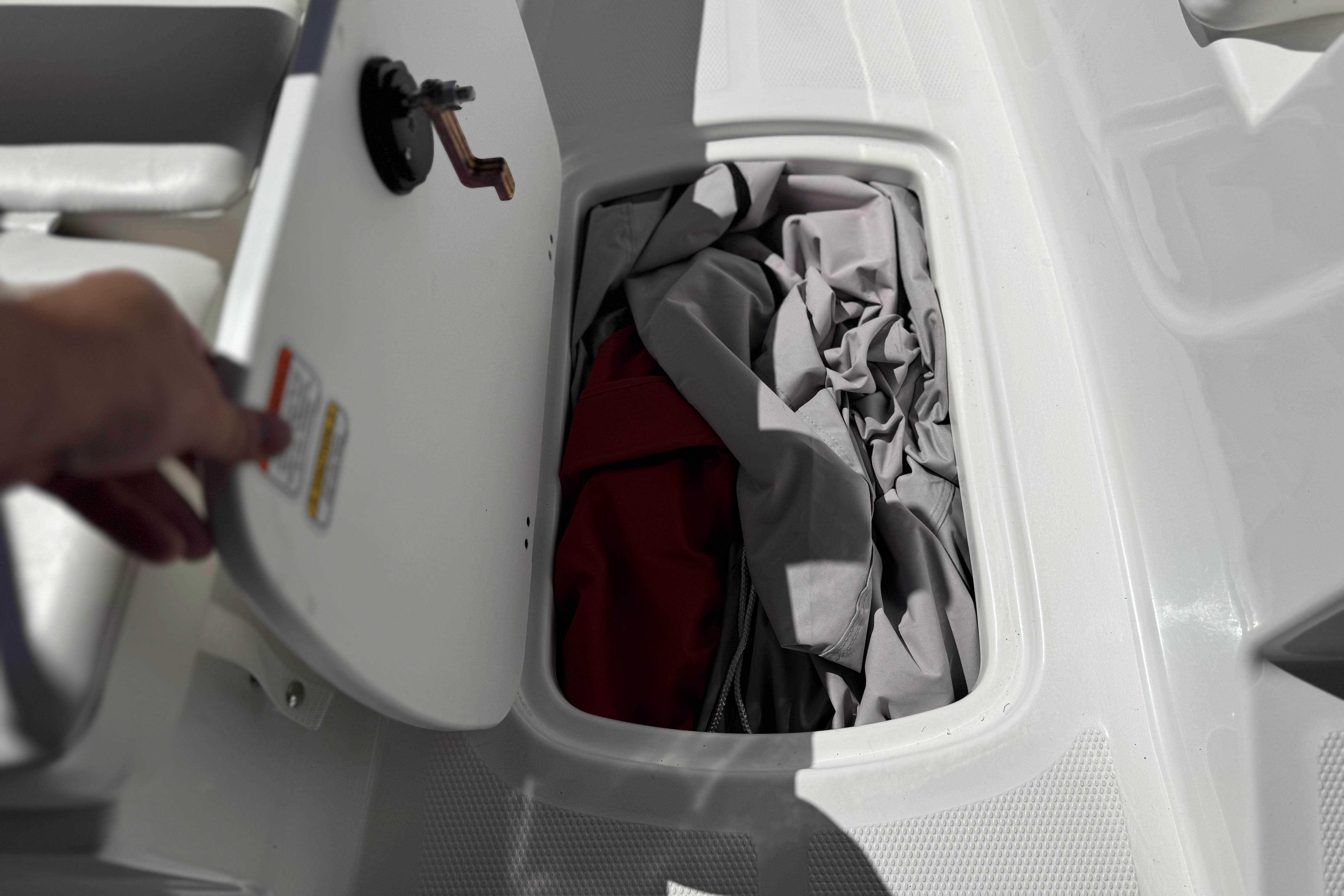 Open storage compartment in 2024 Tahoe T16 boat with fabric inside.