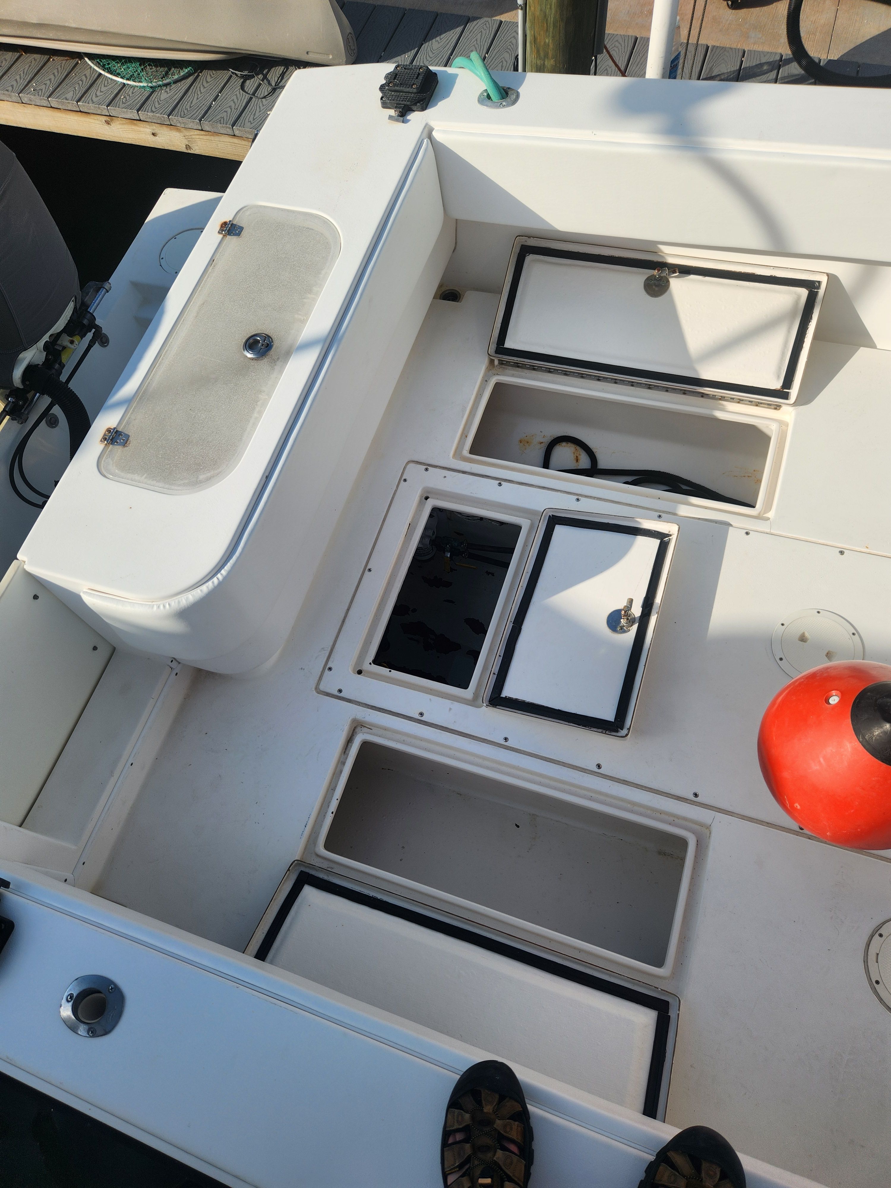 The image shows the deck of a 2005 Contender 27T boat with multiple storage compartments.