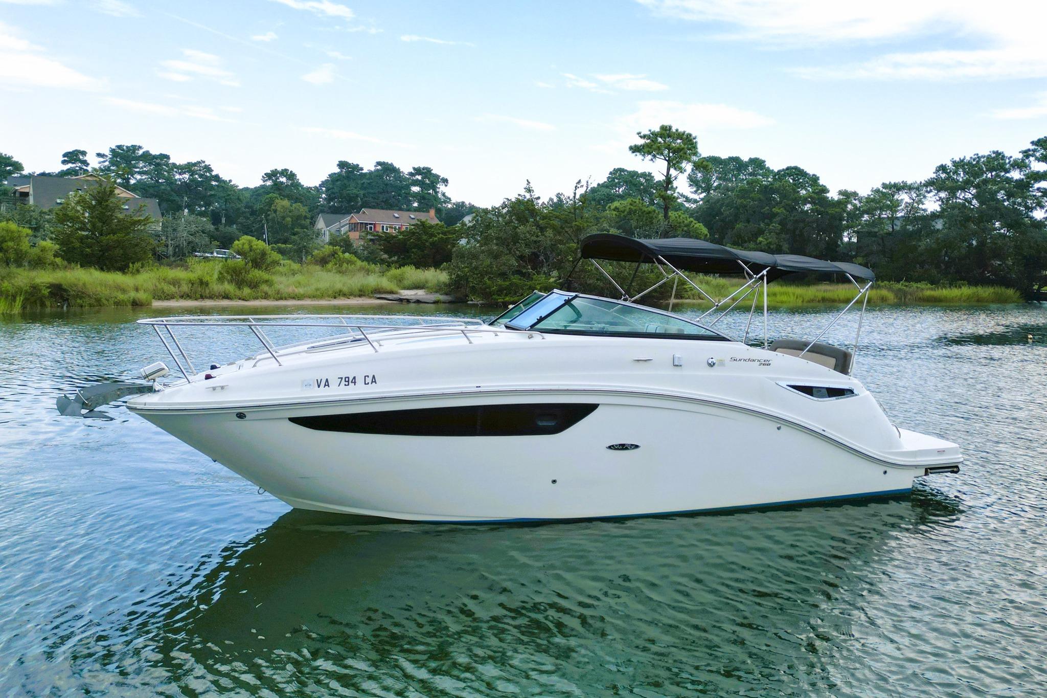 2015 Sea Ray Sundancer 260 boat on calm water, surrounded by lush greenery.