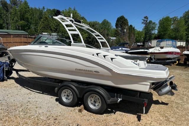 2023 Chaparral 23 SSi boat on trailer, parked outdoors, surrounded by trees and other boats.