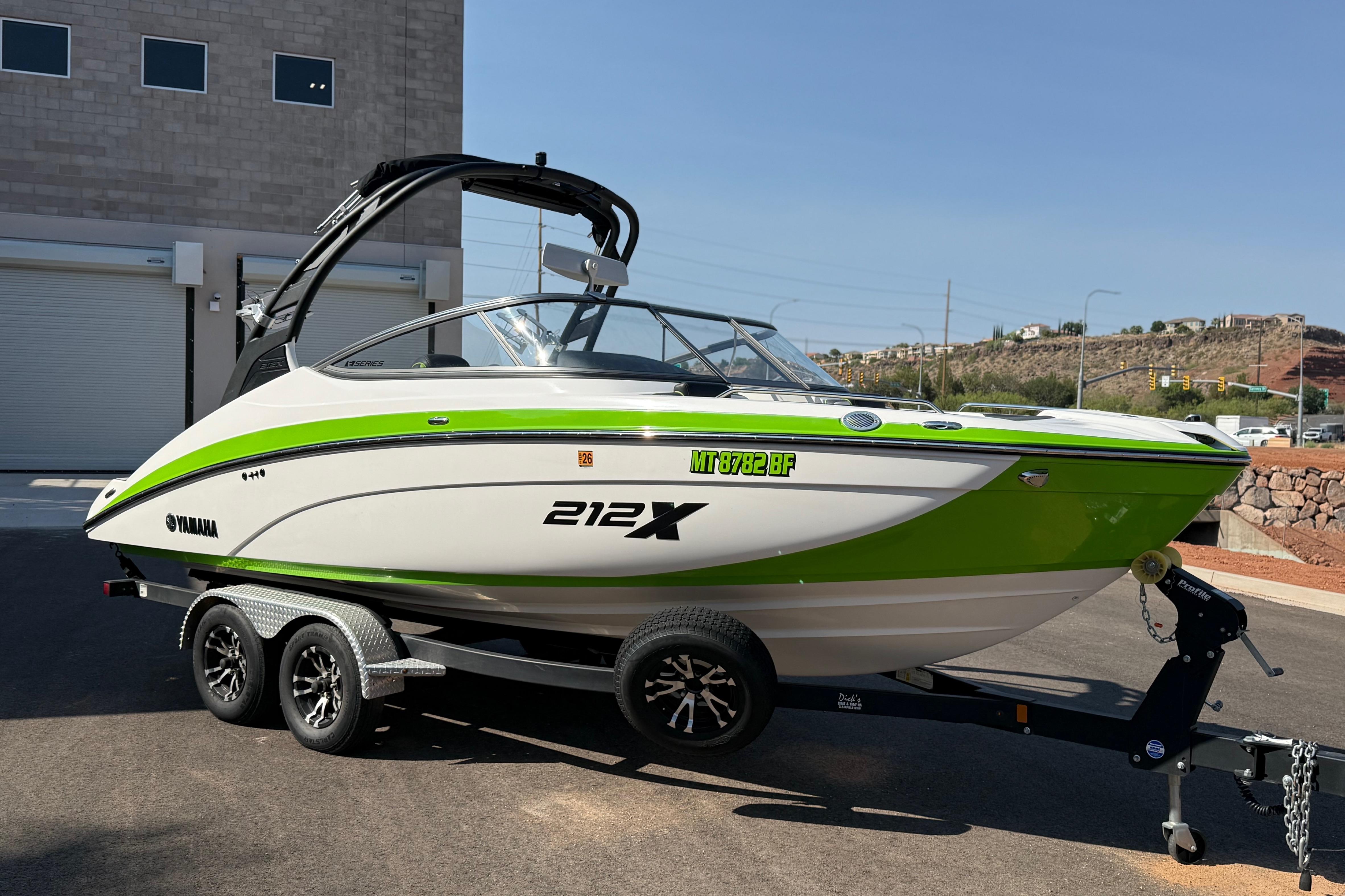 2022 Yamaha Boats 212XE in green and white on a trailer, parked outdoors.