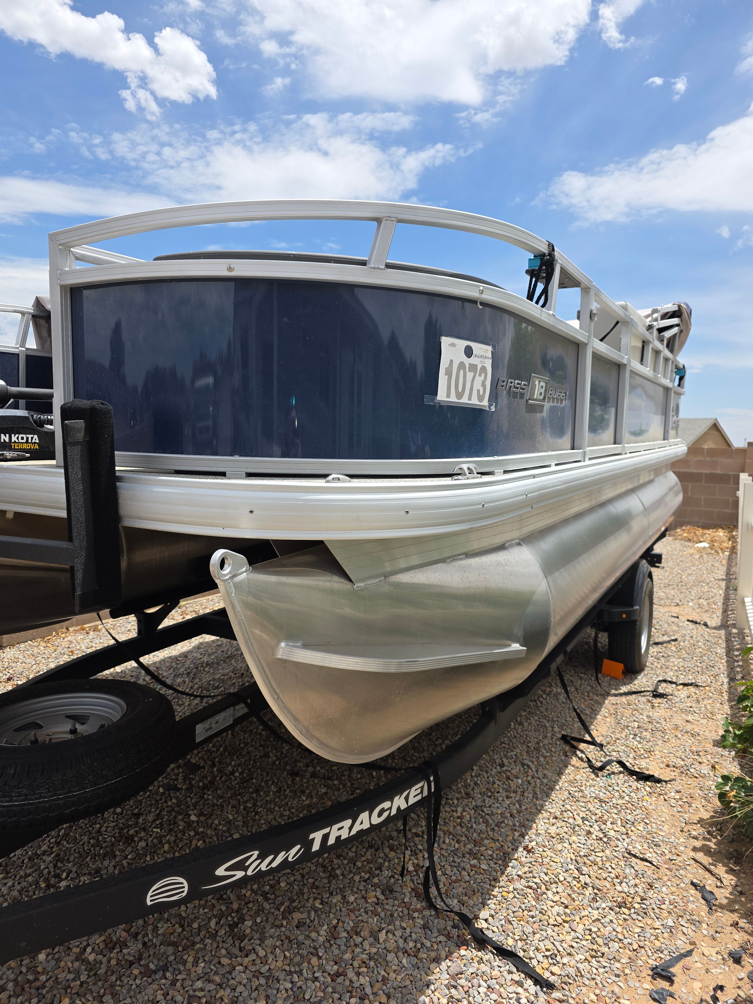 A Sun Tracker Bass Buggy 18 DLX pontoon boat on a trailer, ready for use.