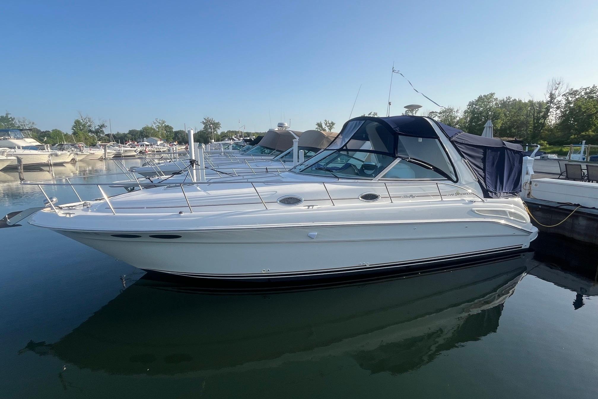 2001 Sea Ray 340 Sundancer yacht docked in a marina under clear blue sky.
