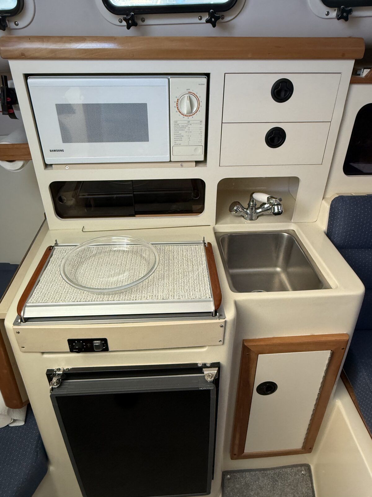 Galley area of a 2001 Albin Tournament Express with microwave, sink, and refrigerator.