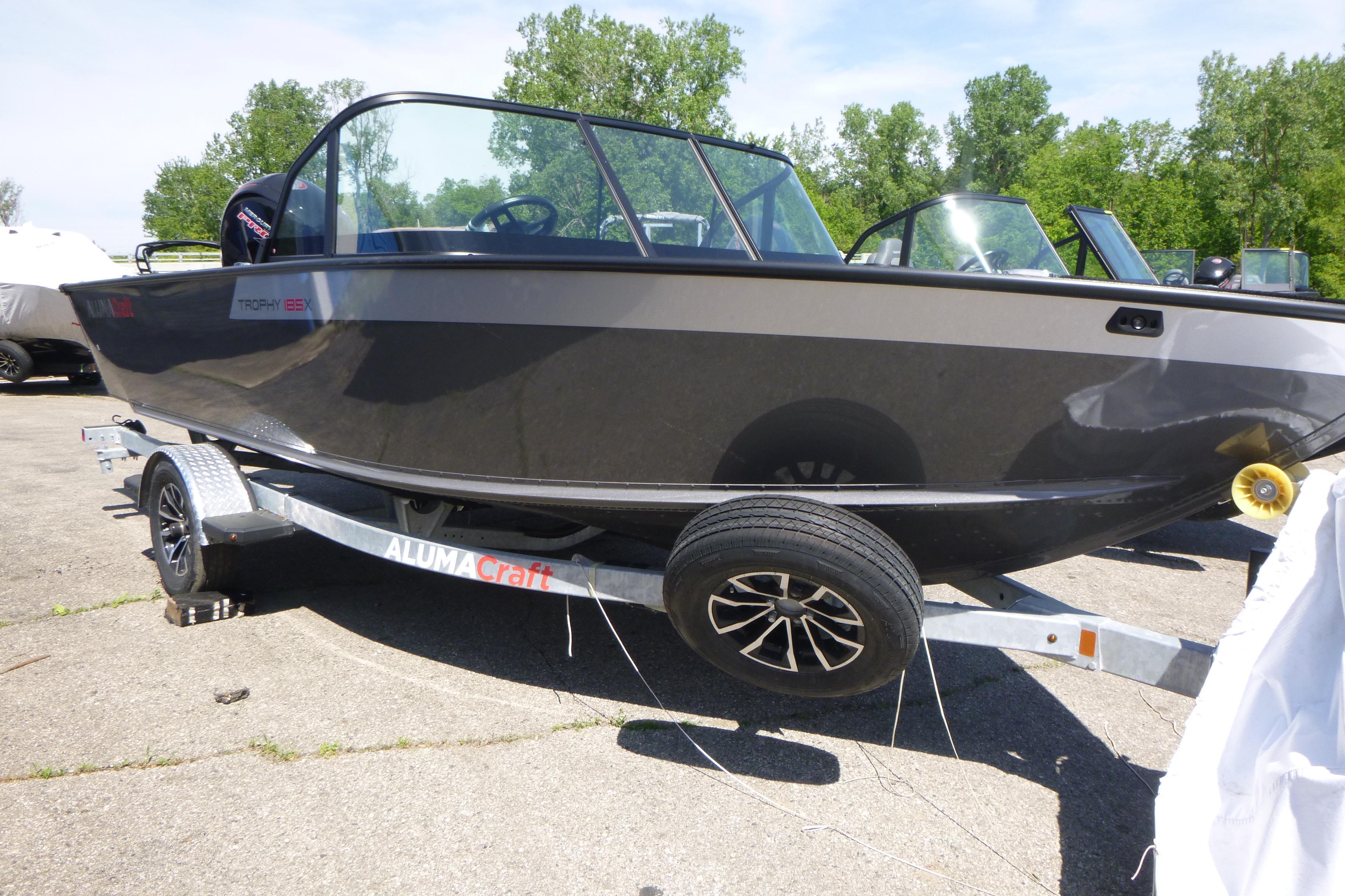 2025 Alumacraft Trophy 185X Sport boat on trailer, parked outdoors.