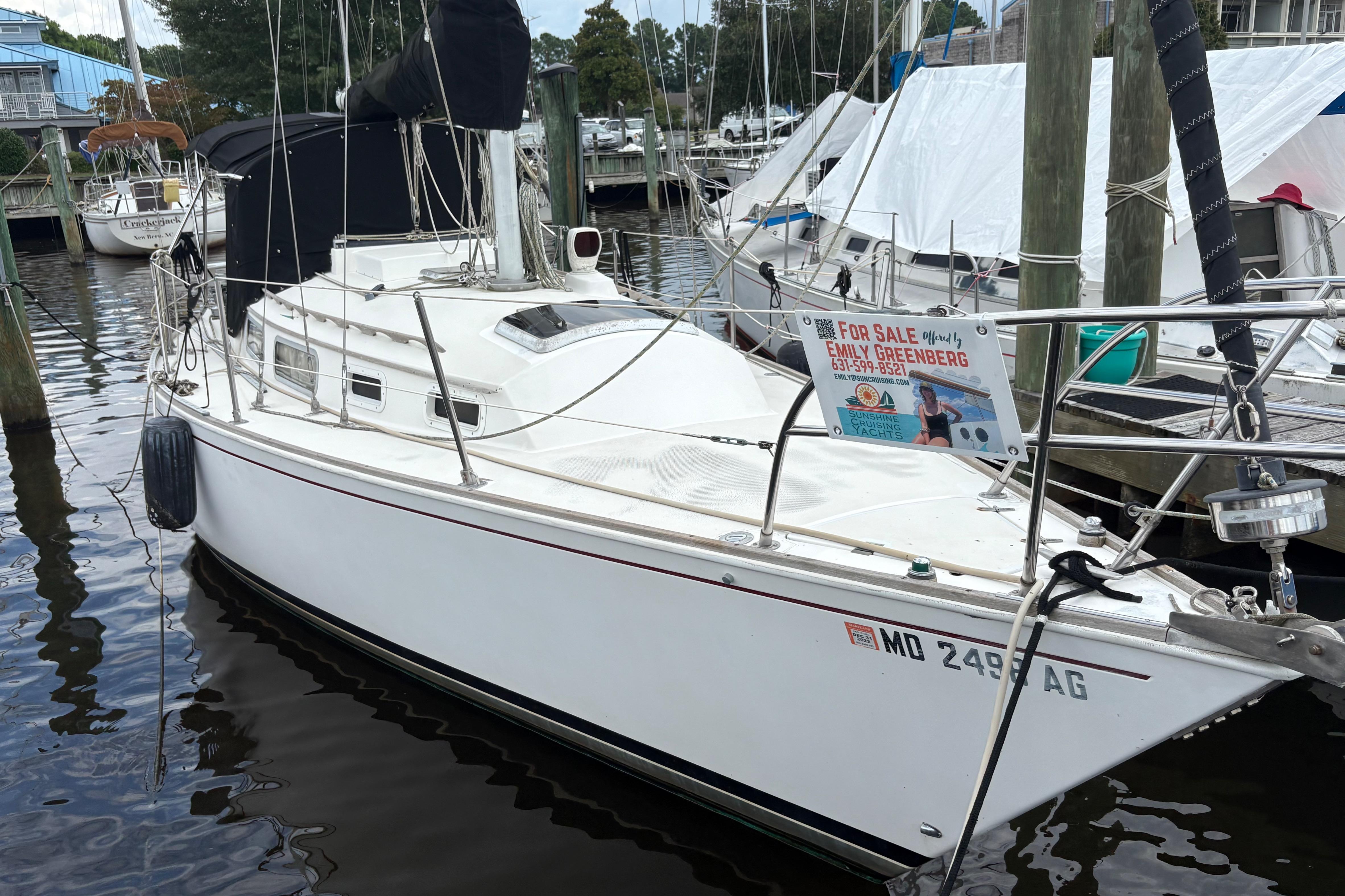 1981 Sabre 31 sailboat docked, for sale sign displayed, marina background.