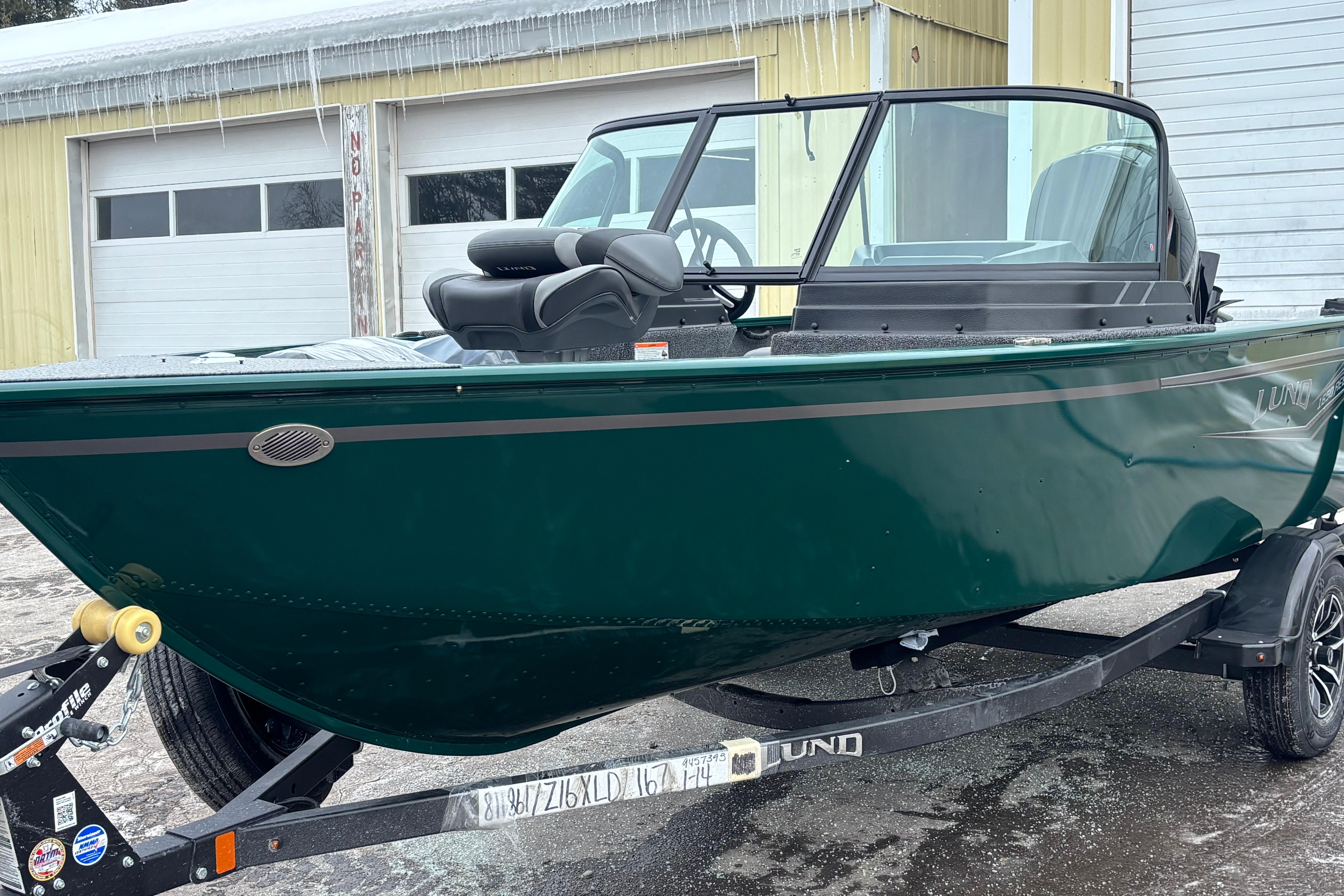 2026 Lund 1650 Rebel XL Sport boat on trailer, parked outside a garage.