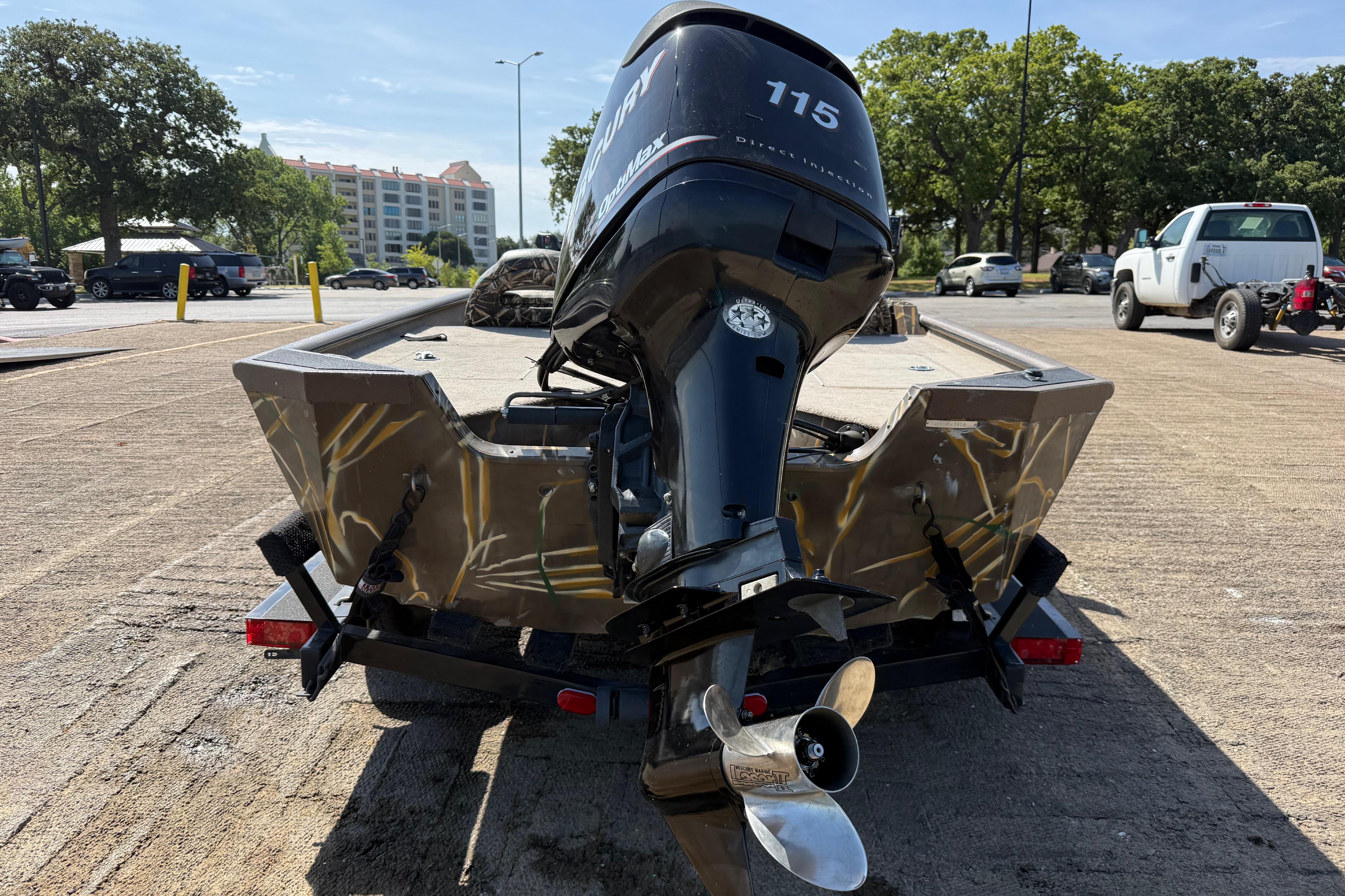 2010 SeaArk Stealth 190 boat with Mercury outboard motor on a trailer in a parking lot.