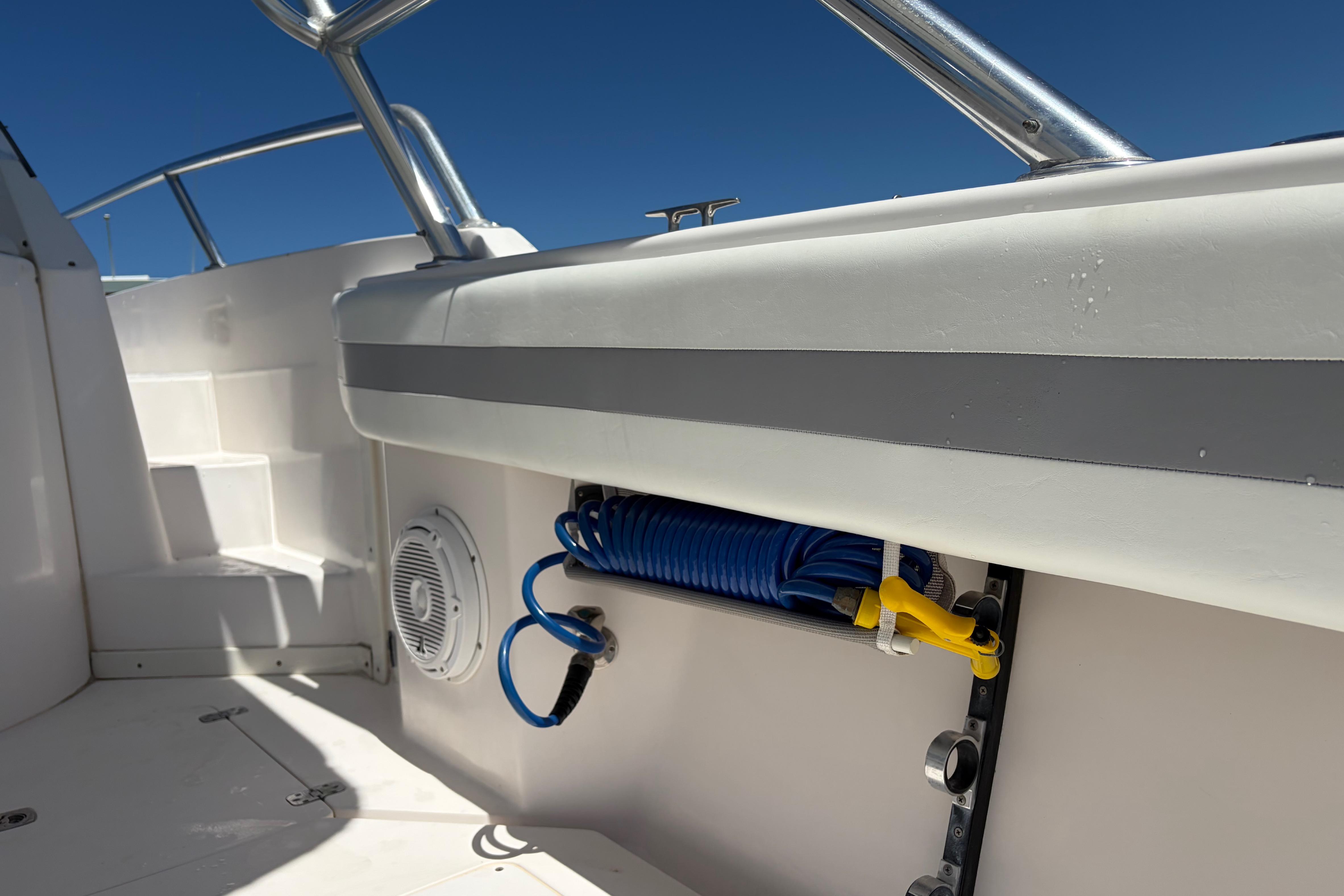 1998 Intrepid 339 Walkaround boat interior with coiled hose and speaker, under clear blue sky.
