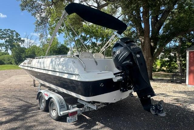 1999 Hurricane SunDeck Sport 201 OB boat on trailer, featuring a powerful outboard motor.