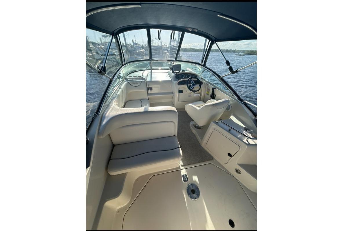 Interior of a Sea Ray 240 Sundancer with white seating and a helm console.