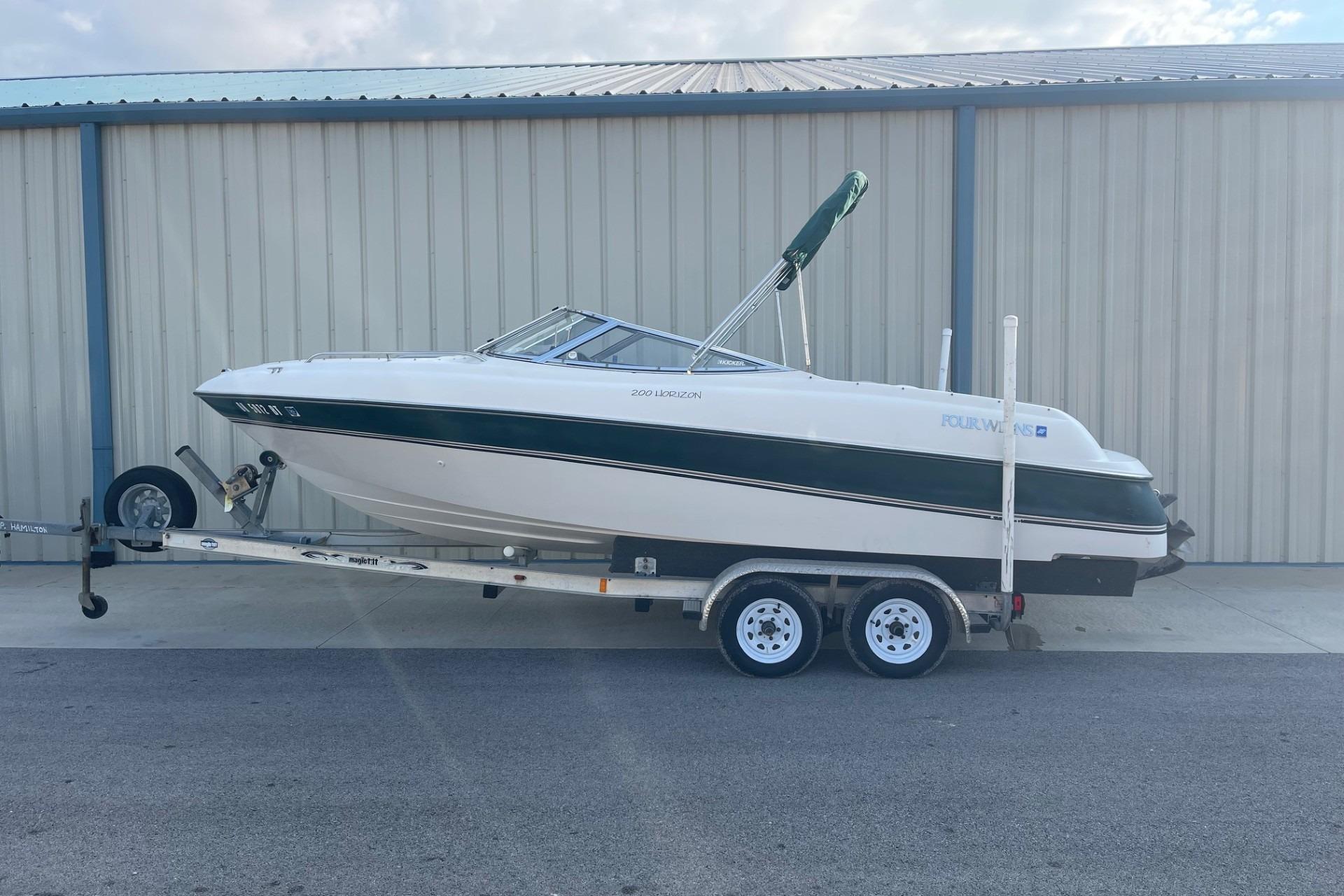 1996 Four Winns 200 Horizon boat on trailer, parked outside a metal building.