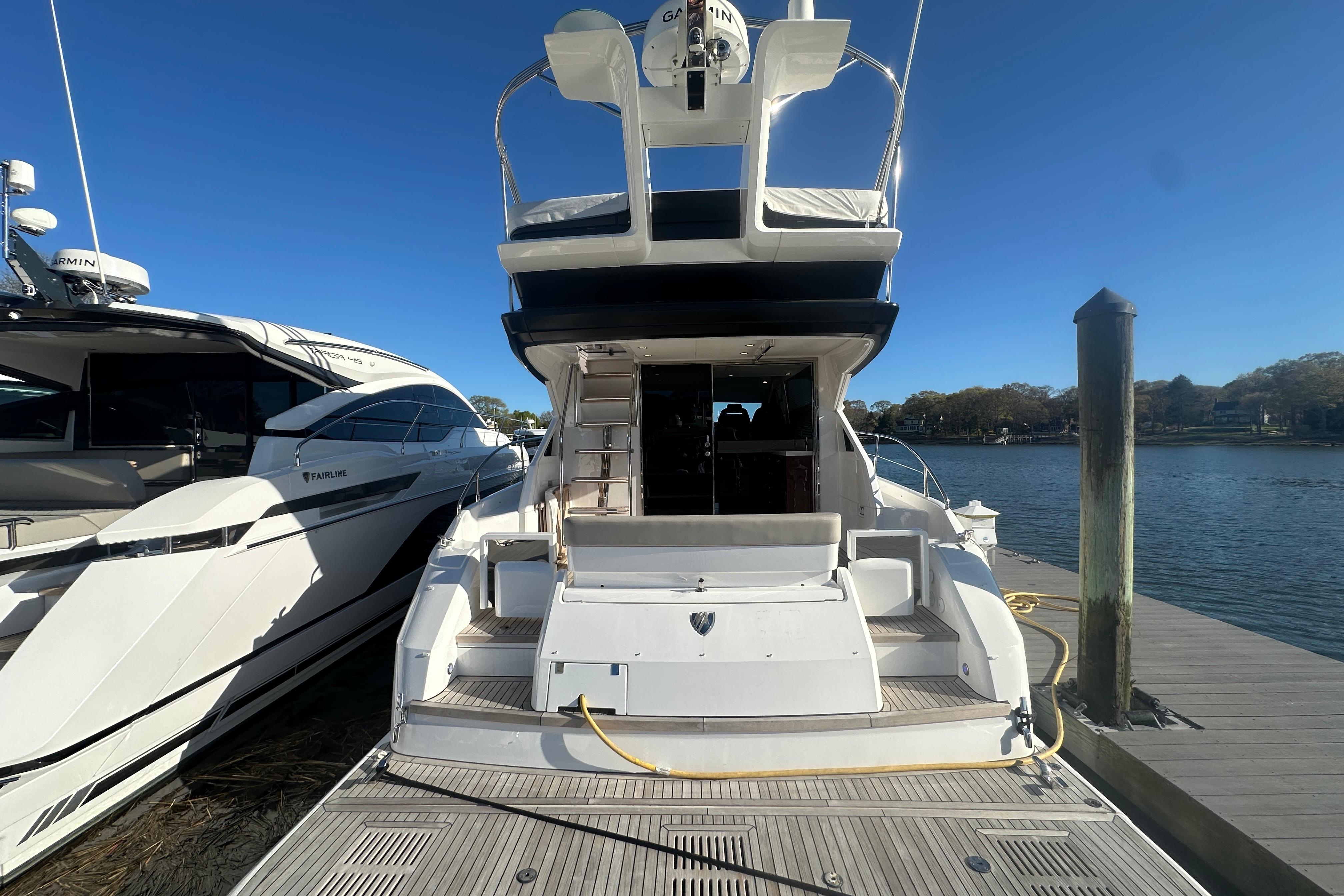 2024 Fairline Squadron 50 yacht docked, rear view, sunny day, calm waters.