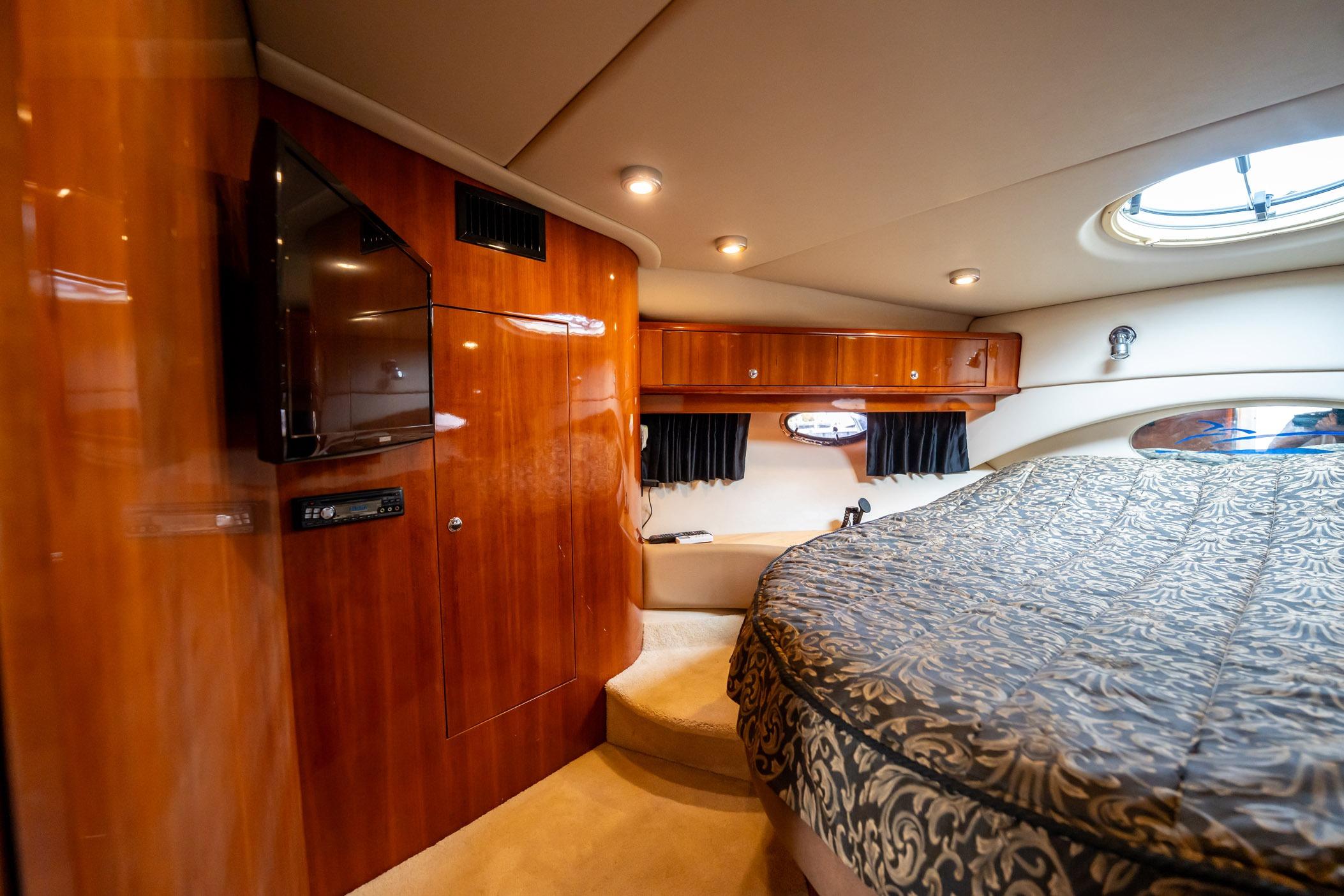 Luxurious 2008 Regal Commodore 4460 yacht interior with wood paneling and elegant bedding.