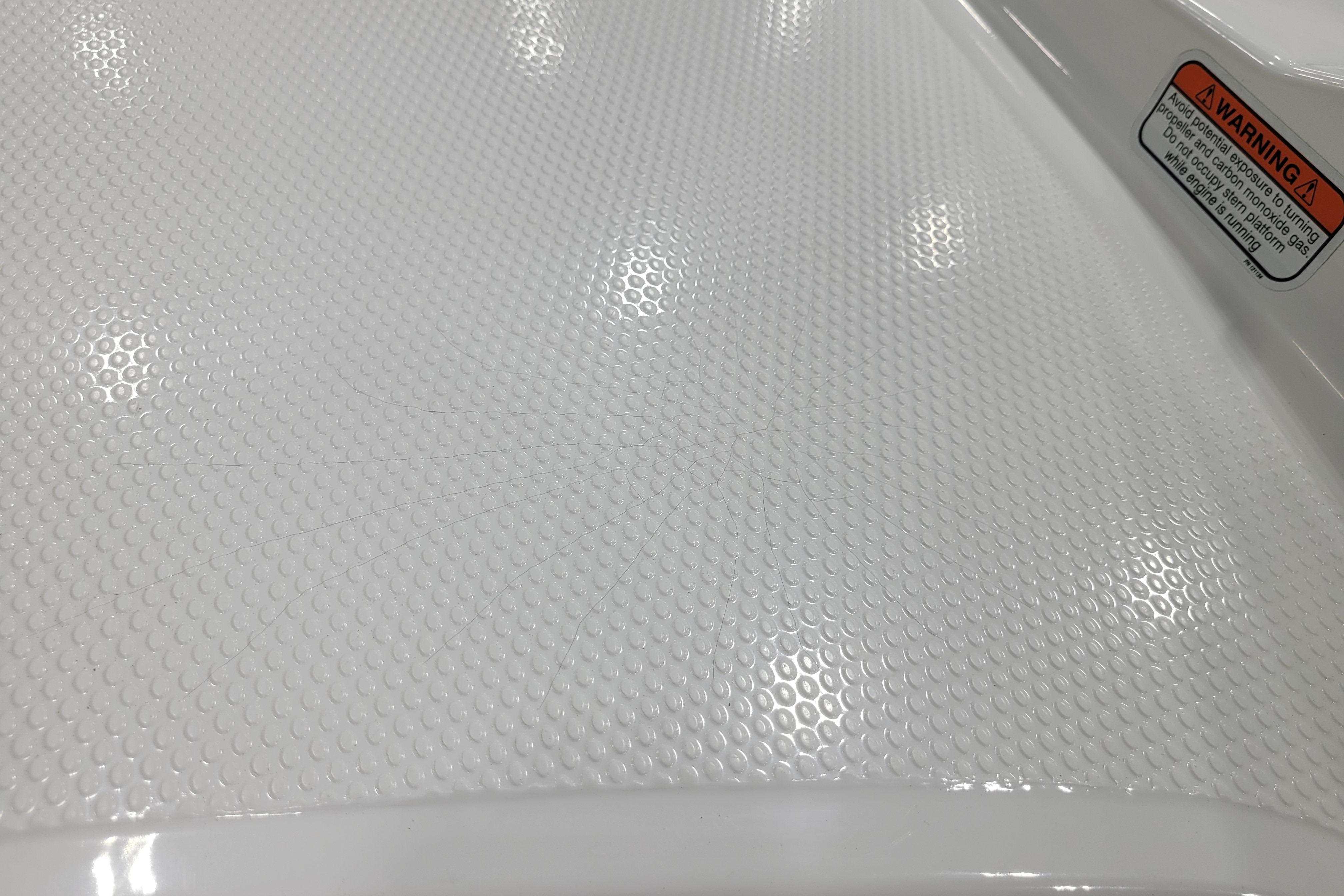 Textured white surface of a 2026 Tahoe 2150 boat with warning label.