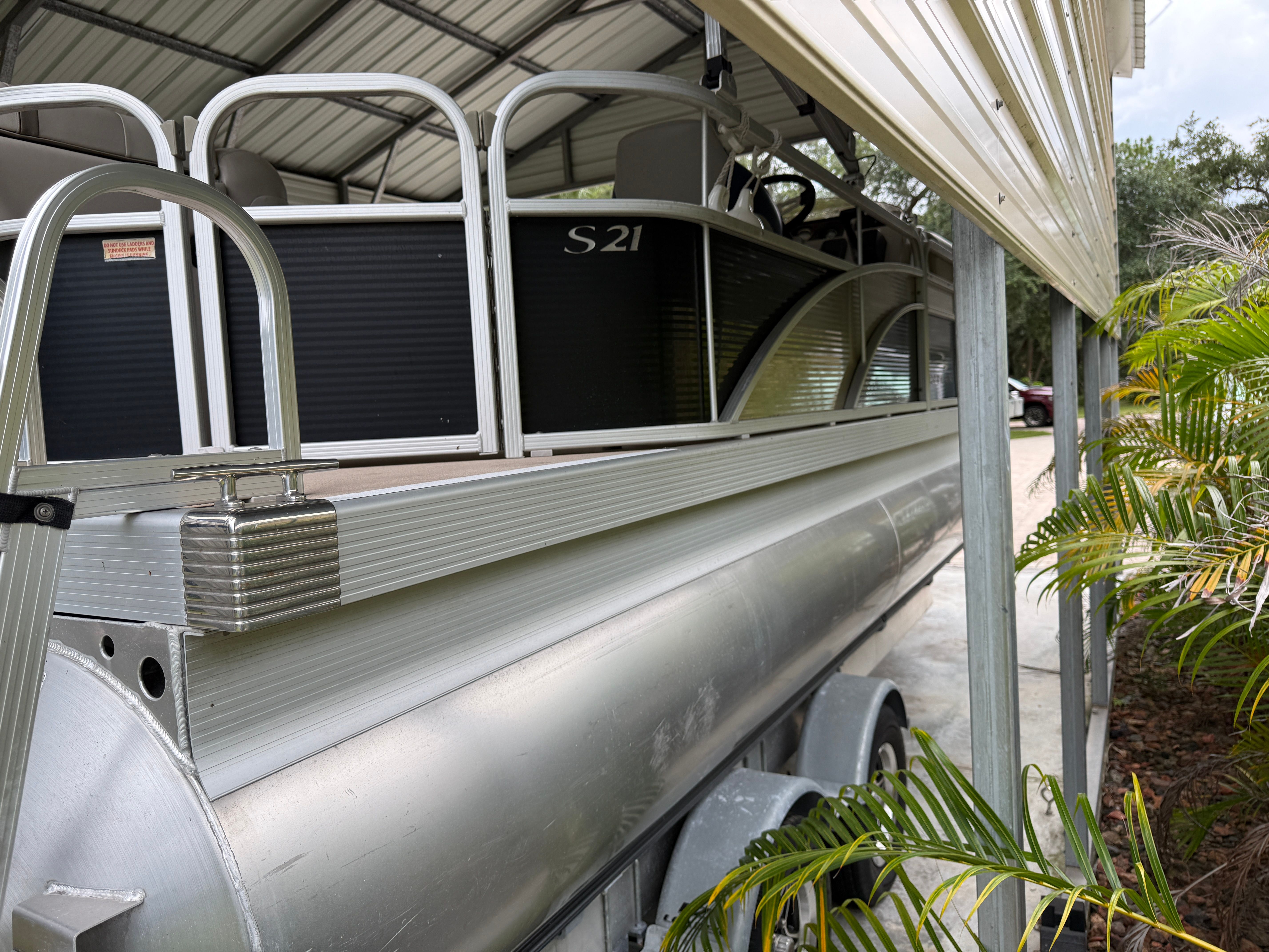 A 2015 Bennington 21SLX pontoon boat is parked under a covered area.