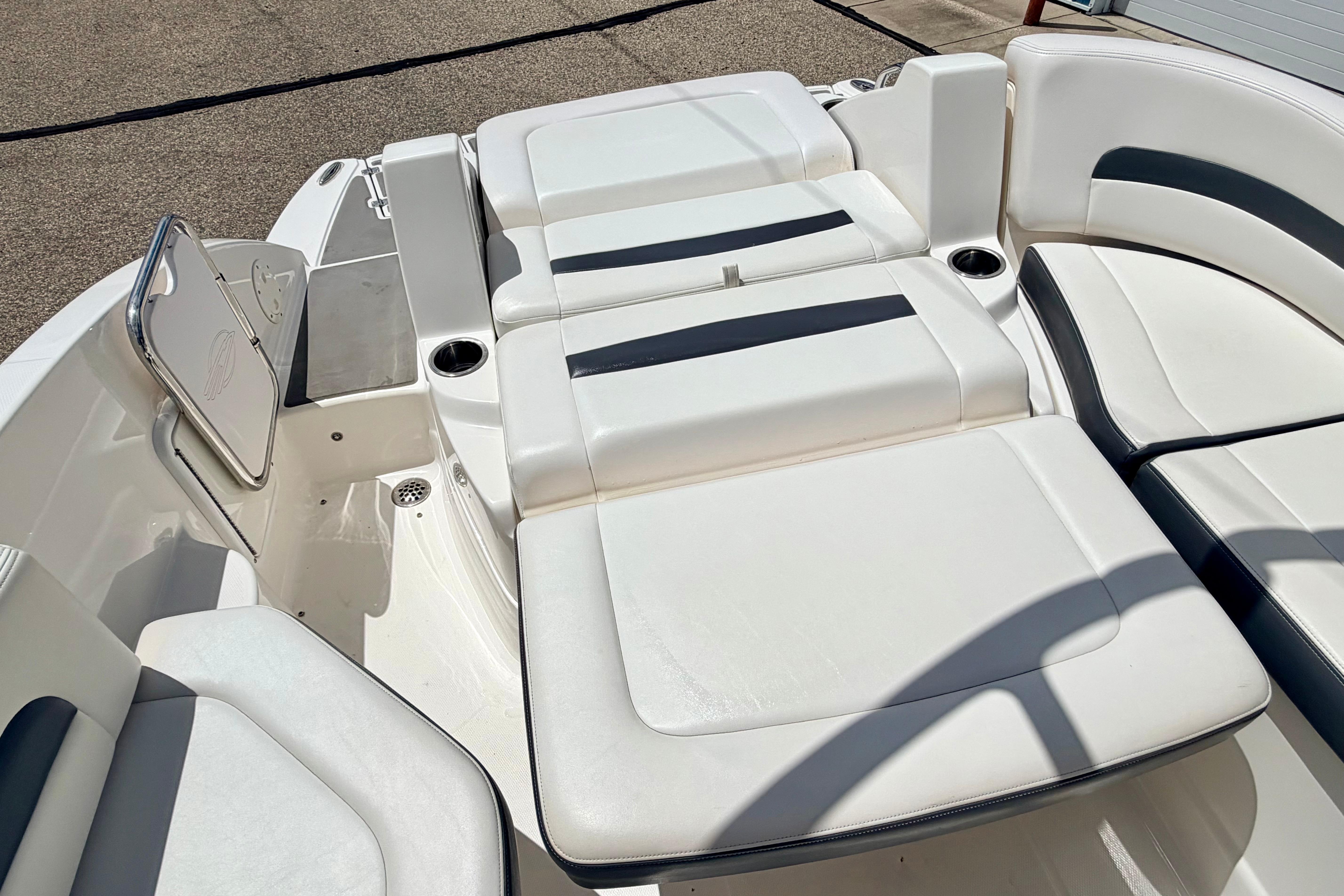 2015 Chaparral Sunesta 264 boat interior with white cushioned seating and cup holders.