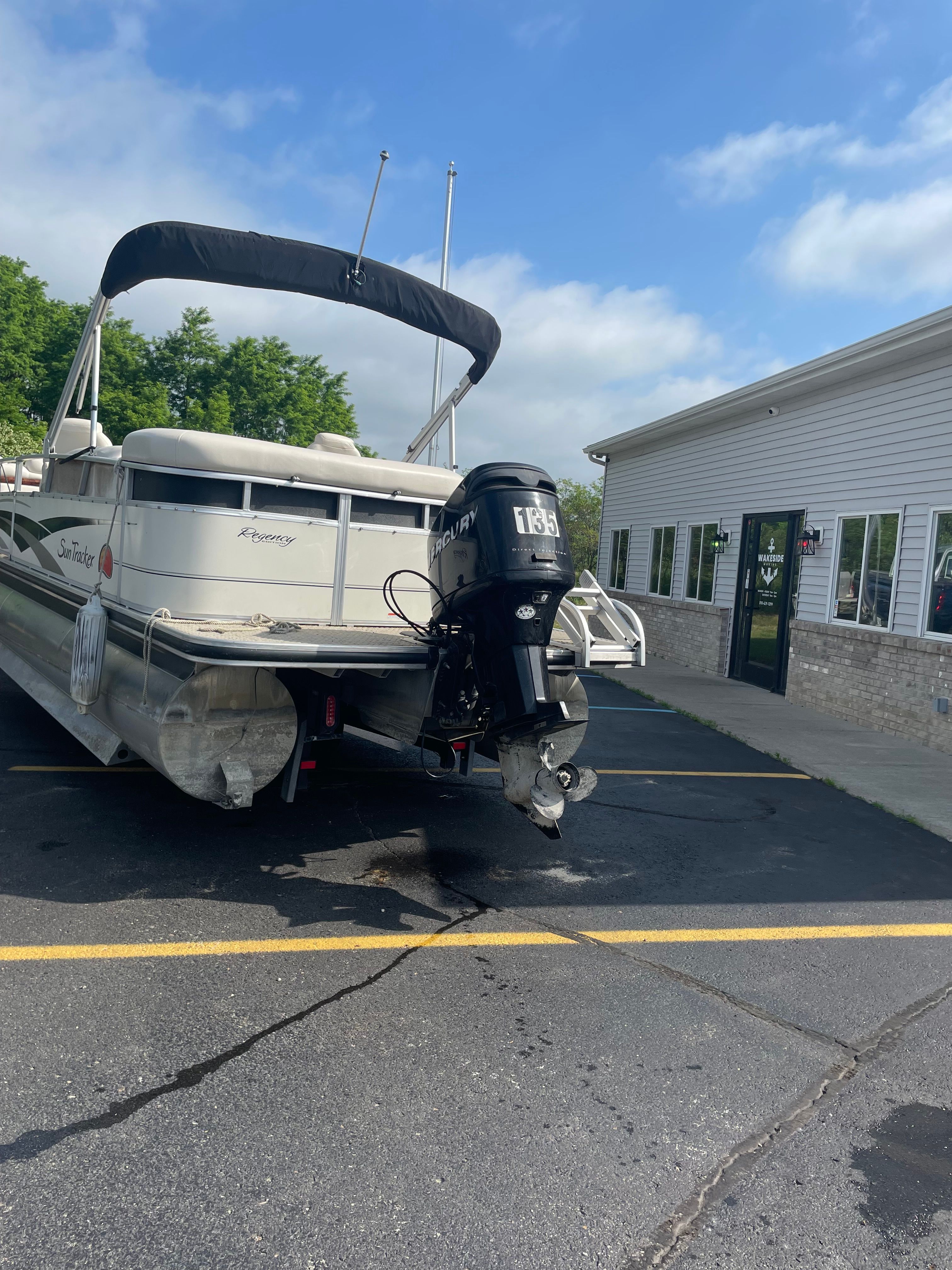 A party boat in a parking lot, featuring an outboard motor and a sunshade.