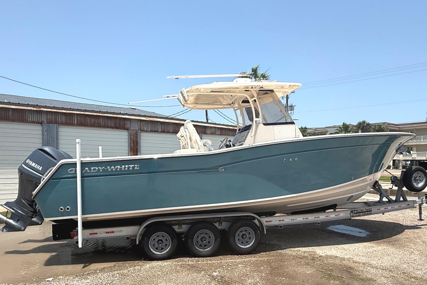 2018 Grady-White Canyon 306 boat on trailer, featuring Yamaha engines, parked outdoors.