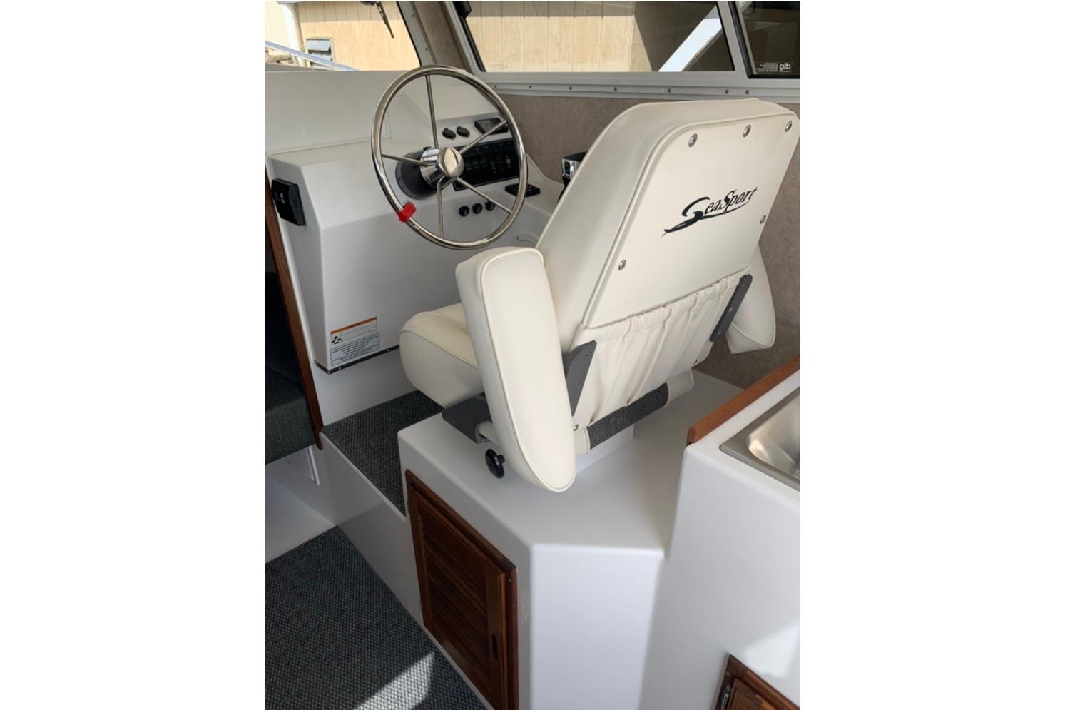 Interior of 2026 Sea Sport Kenai 2600 boat with steering wheel and captain's chair.
