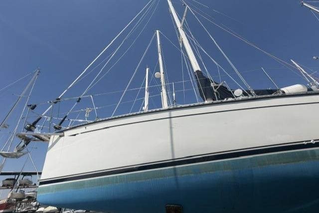 2002 Saga 43 sailboat with white hull and blue bottom, docked under clear sky.