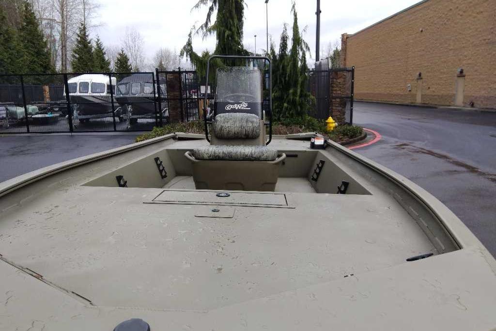 2026 Tracker Grizzly 1860 CC boat in parking lot, showcasing spacious deck and seating.
