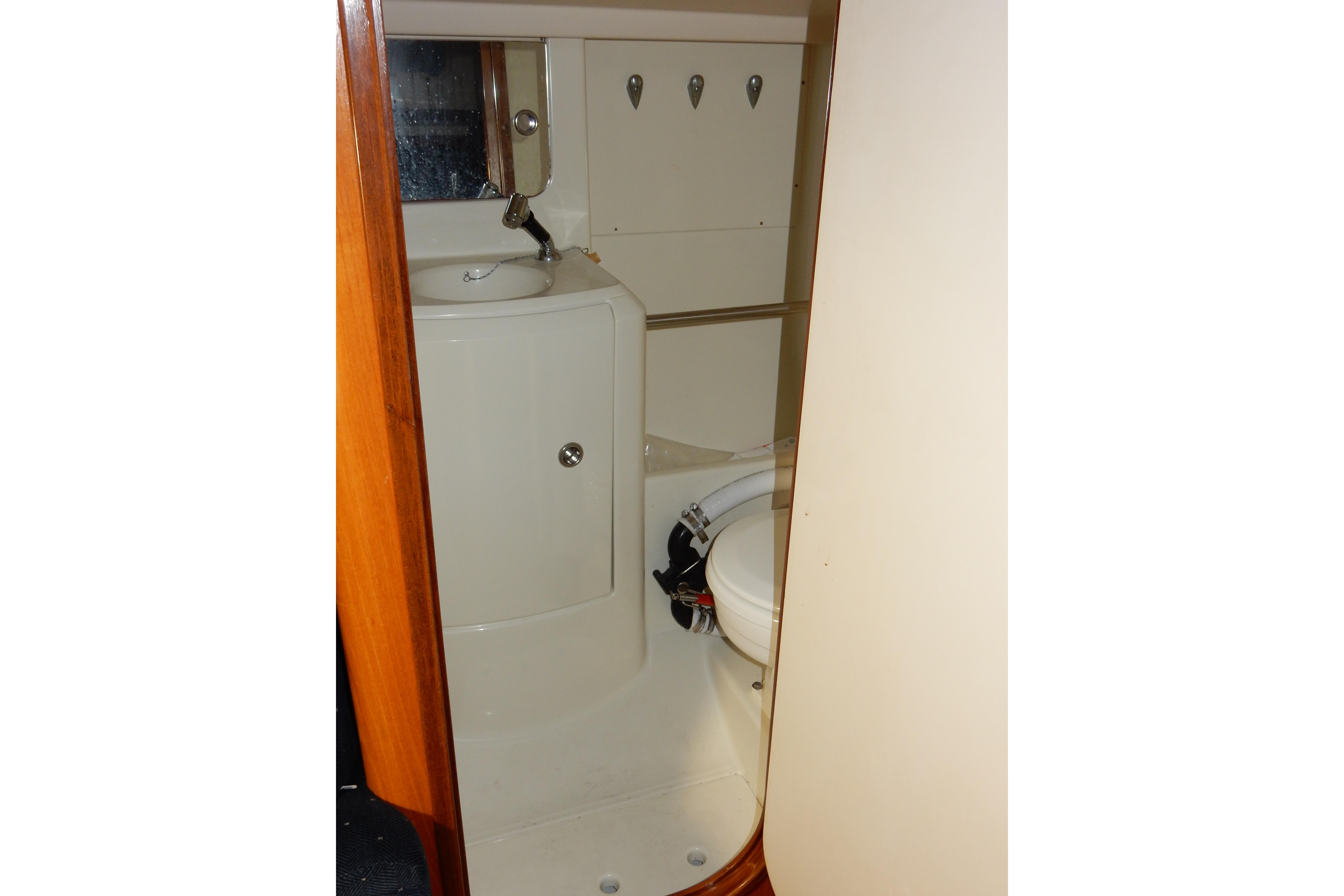 Bathroom interior of 1991 Beneteau Oceanis 370 sailboat, featuring compact sink and toilet.