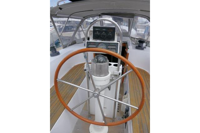 1986 Tayana 52 Center Cockpit sailboat helm with wooden wheel and navigation instruments.