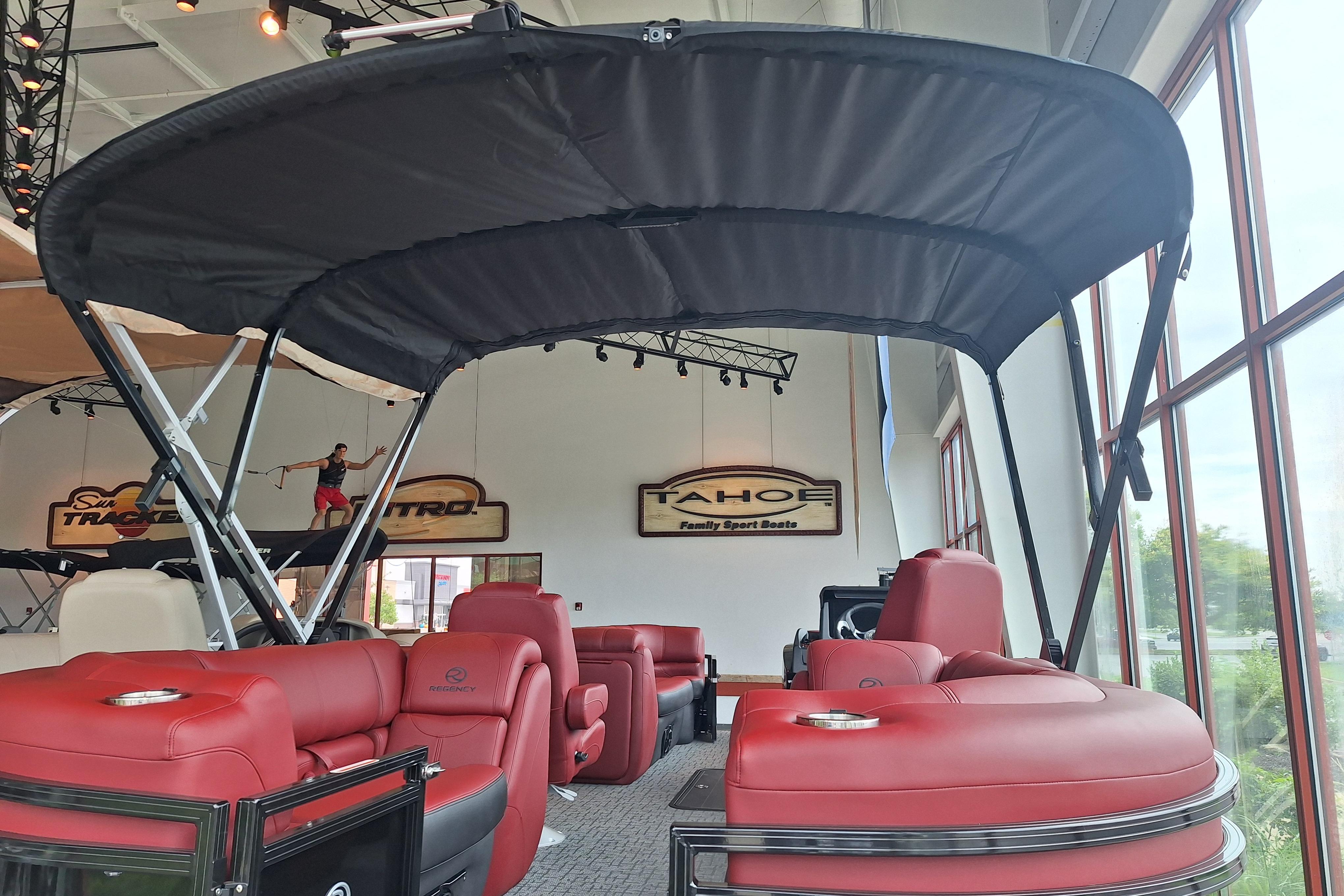 2026 Regency 230 DL pontoon boat with red seating and canopy in showroom.