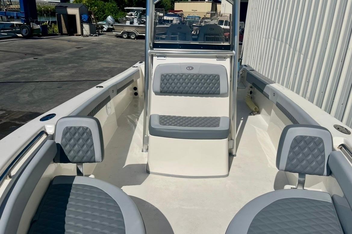 2025 Defiance Catalina 240 boat interior with gray cushioned seating in a marina setting.