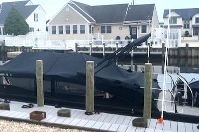 2023 Barletta L23U pontoon boat covered at a dock, with waterfront homes in the background.