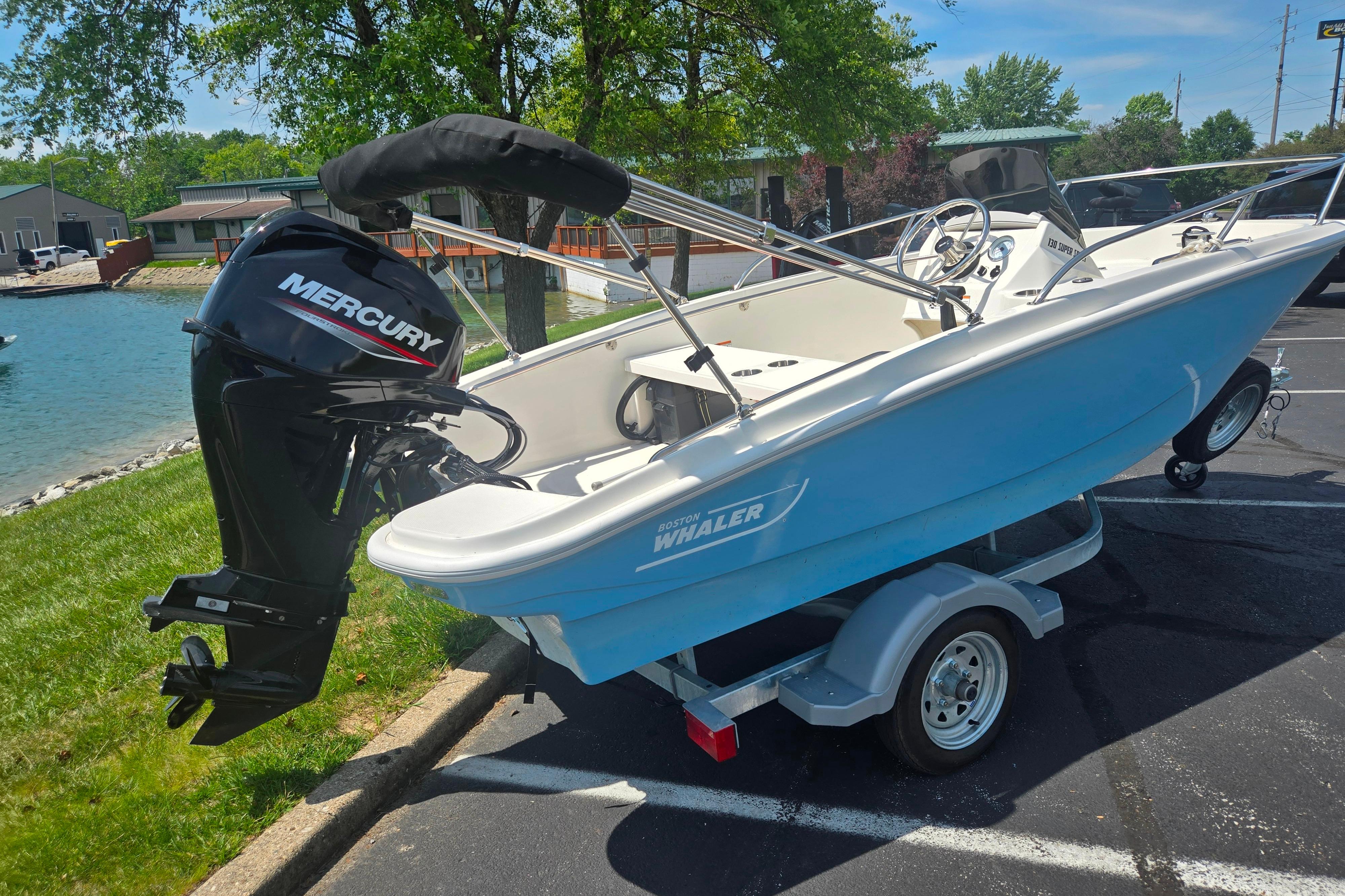 2025 Boston Whaler 130 Super Sport boat with Mercury engine on trailer by water.