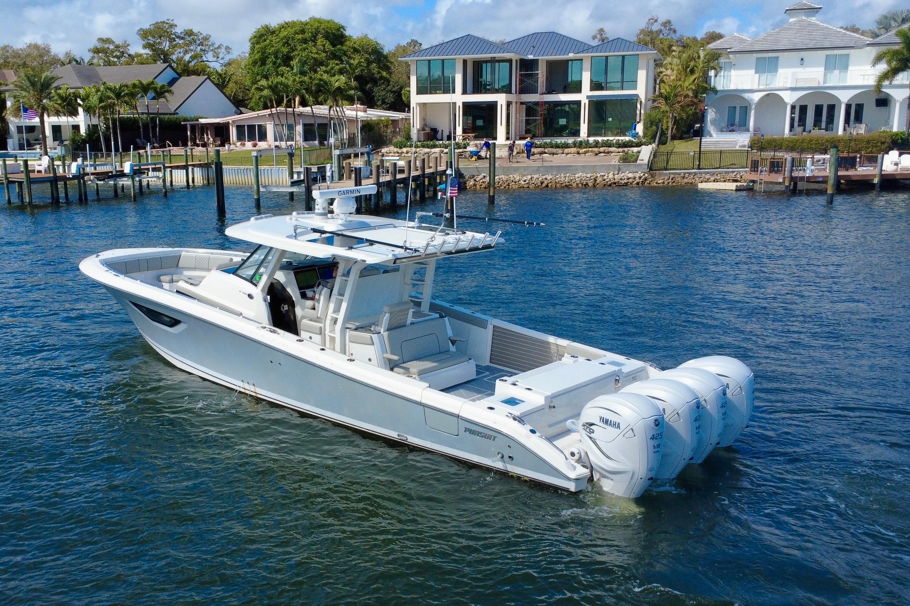 2022 Pursuit S 428 Sport boat cruising near waterfront homes.