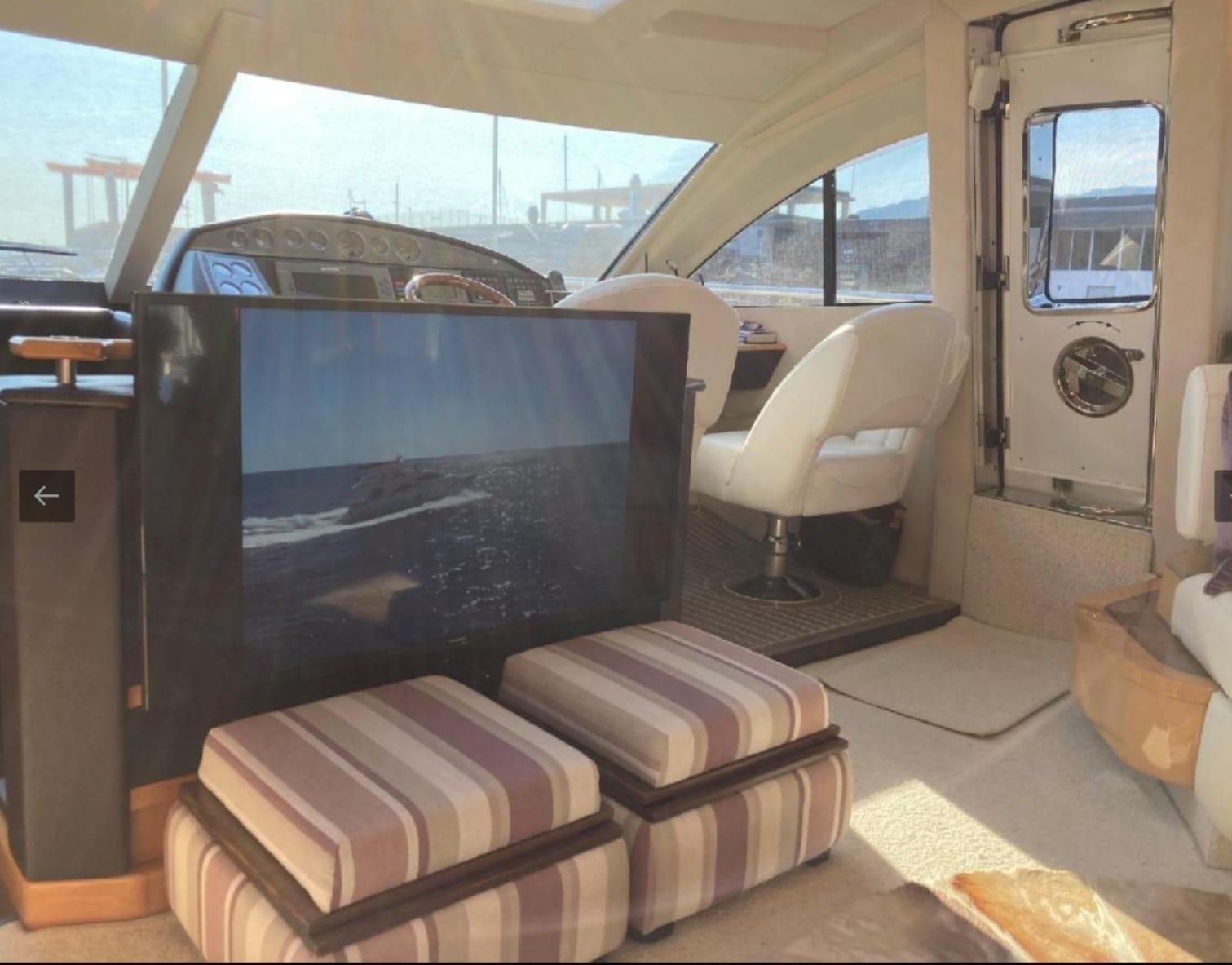 Luxurious interior of a 2005 Sealine T60 yacht with plush seating and a flat-screen TV.