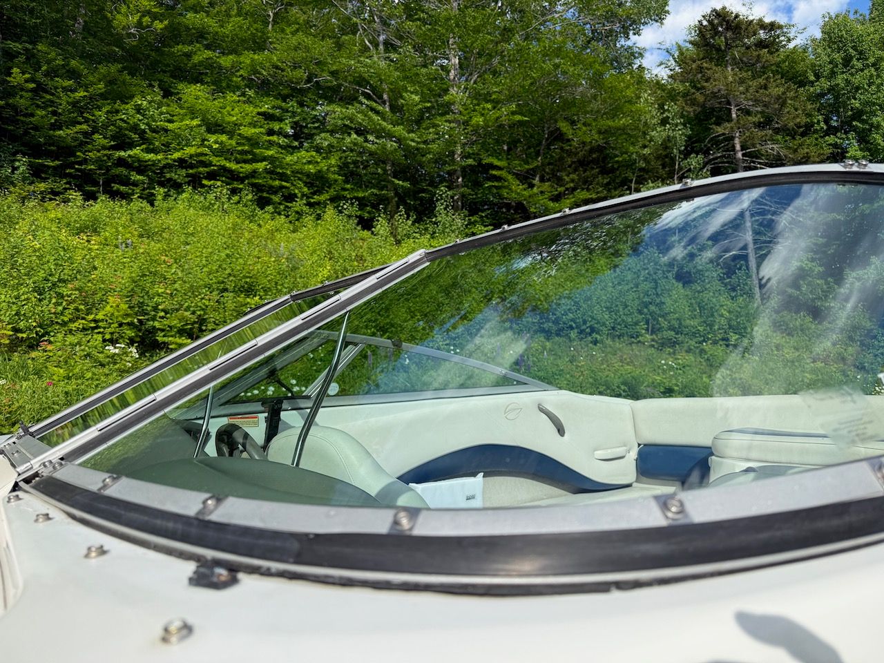 2000 Crownline 192 BR boat parked in lush greenery.