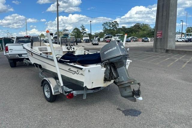 1989 Henry O 150 Dual Console boat on trailer, parked in a lot under a cloudy sky.