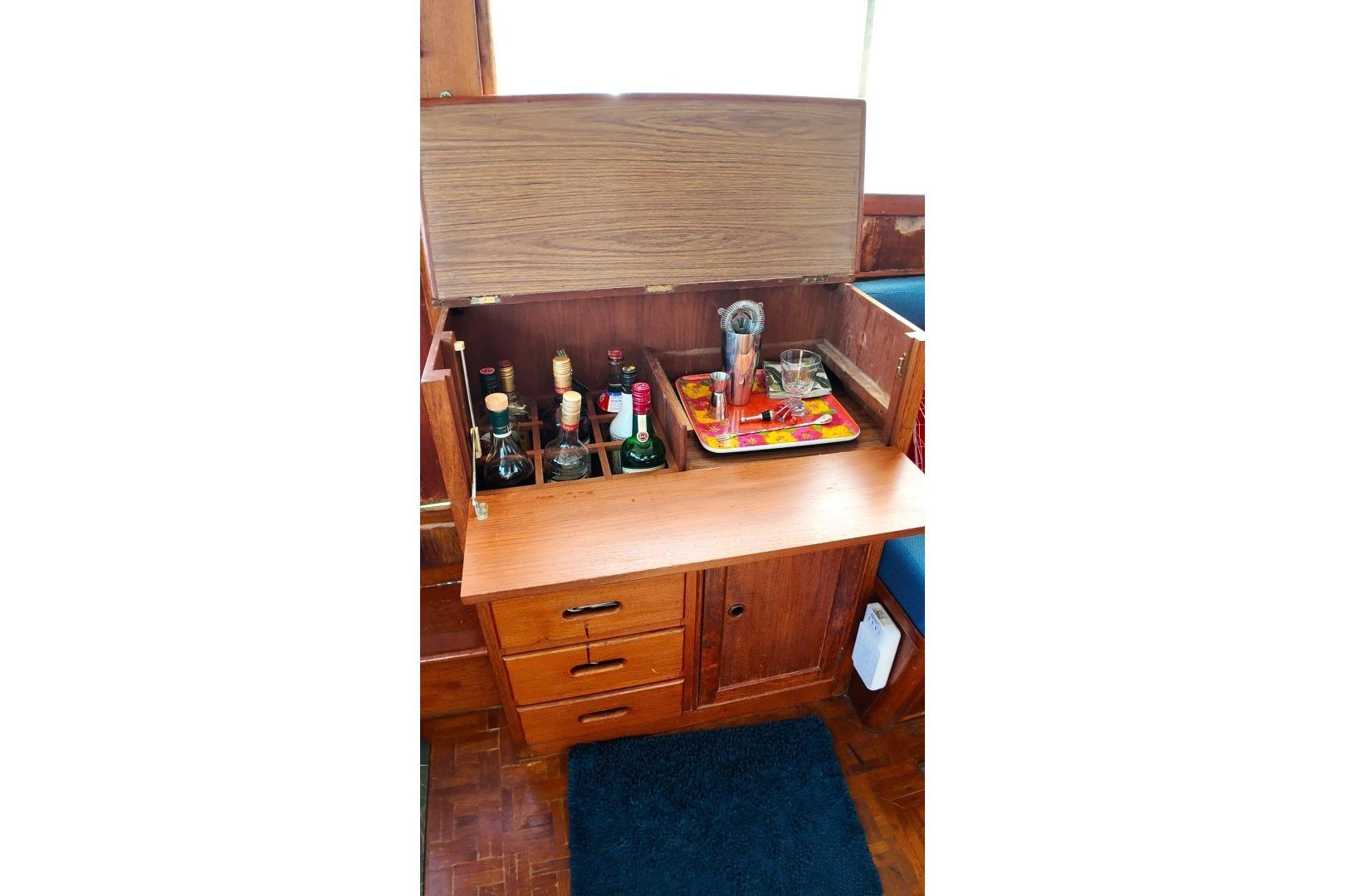 1978 Grand Banks 42 Classic yacht interior with a wooden bar cabinet and liquor bottles.