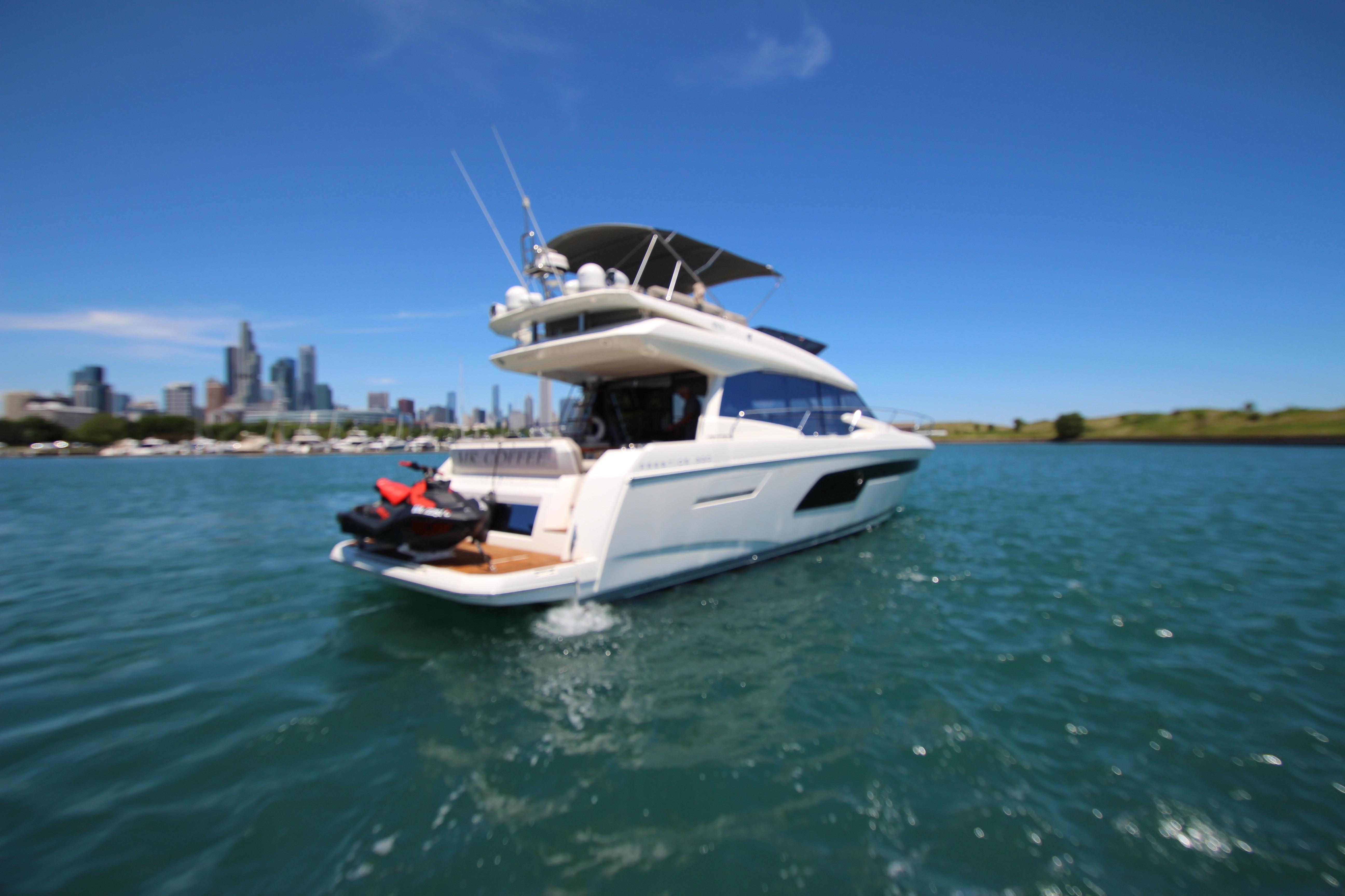 2022 Prestige 520 yacht cruising on a sunny day with city skyline in background.