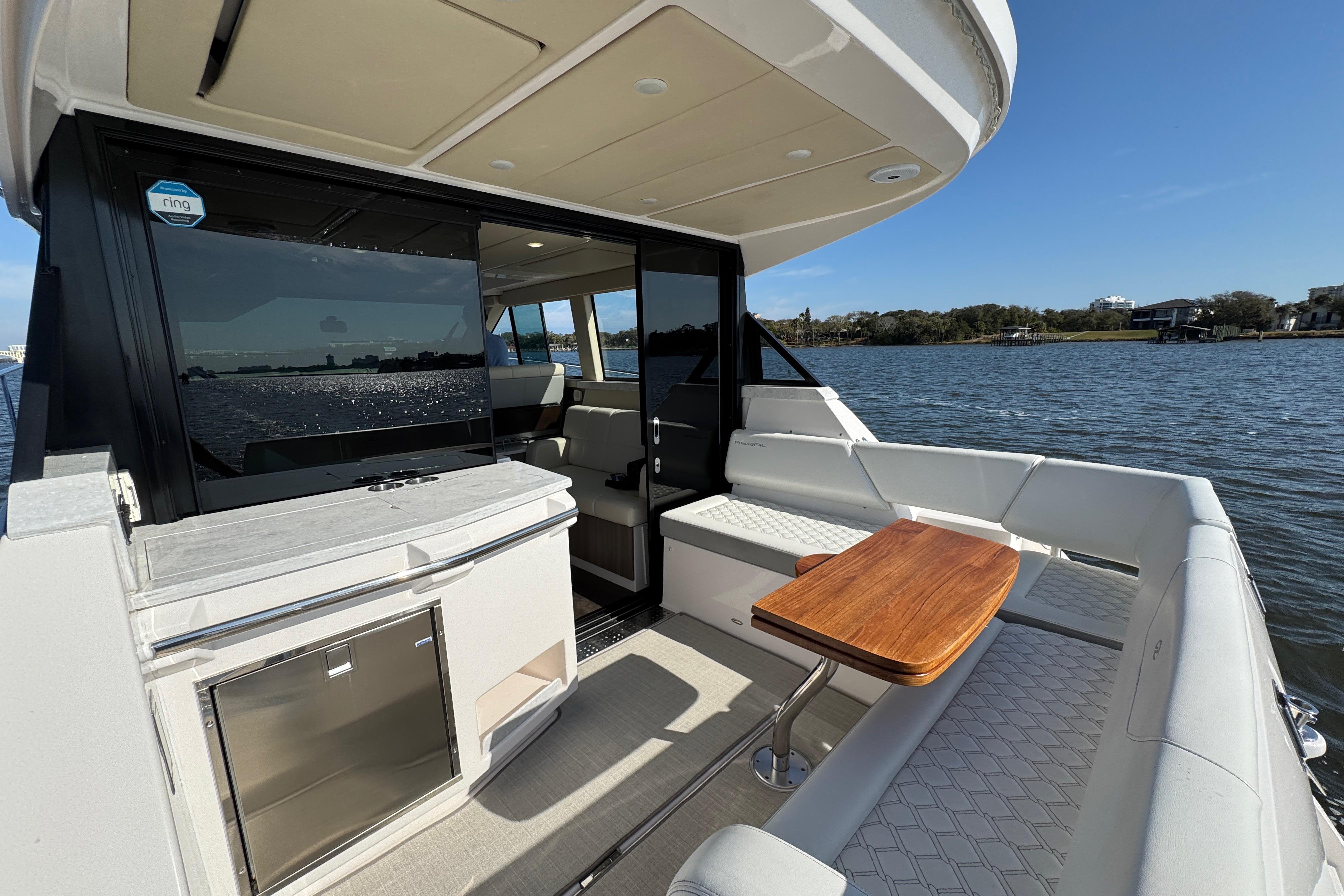 2021 Regal 38 XO yacht interior with seating, table, and water view.