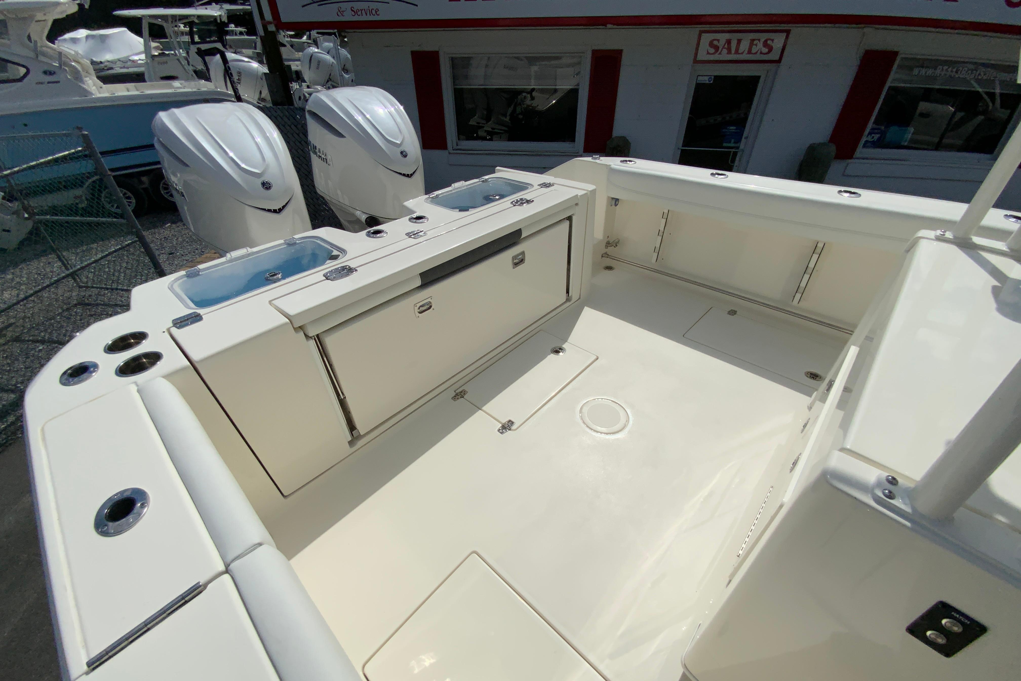 2027 Cobia 320 Center Console boat deck with twin engines and storage compartments.