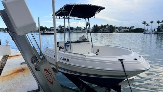 A 2004 Wellcraft 180 Fisherman on a boat lift by the water.