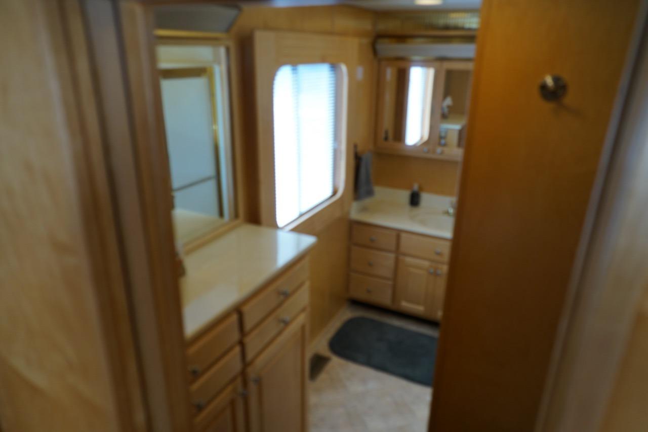 Interior of 2000 Stardust Cruisers houseboat bathroom with wooden cabinetry and mirror.