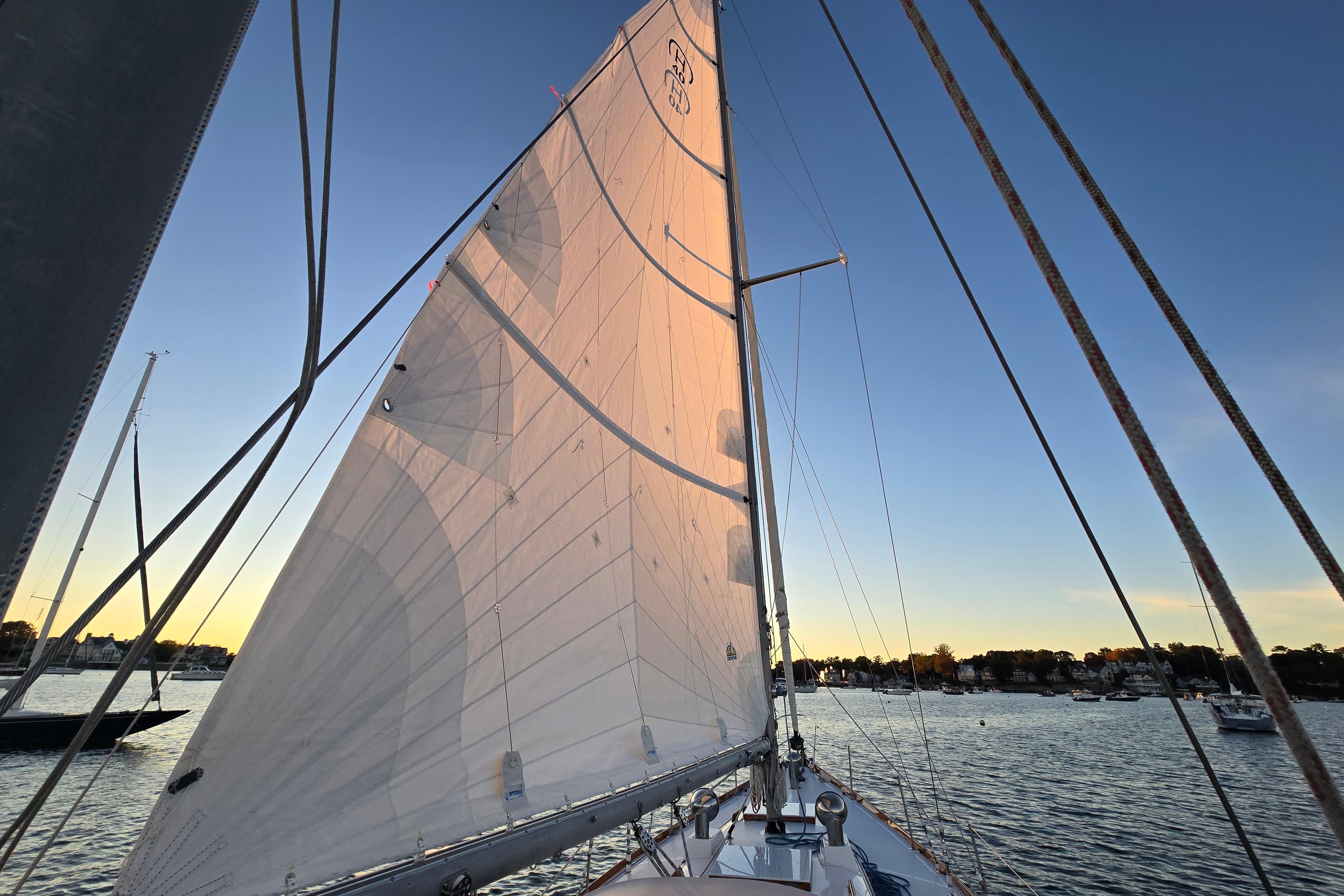 Sailing on a 1970 Hinckley Bermuda 40 at sunset, showcasing its majestic sails.