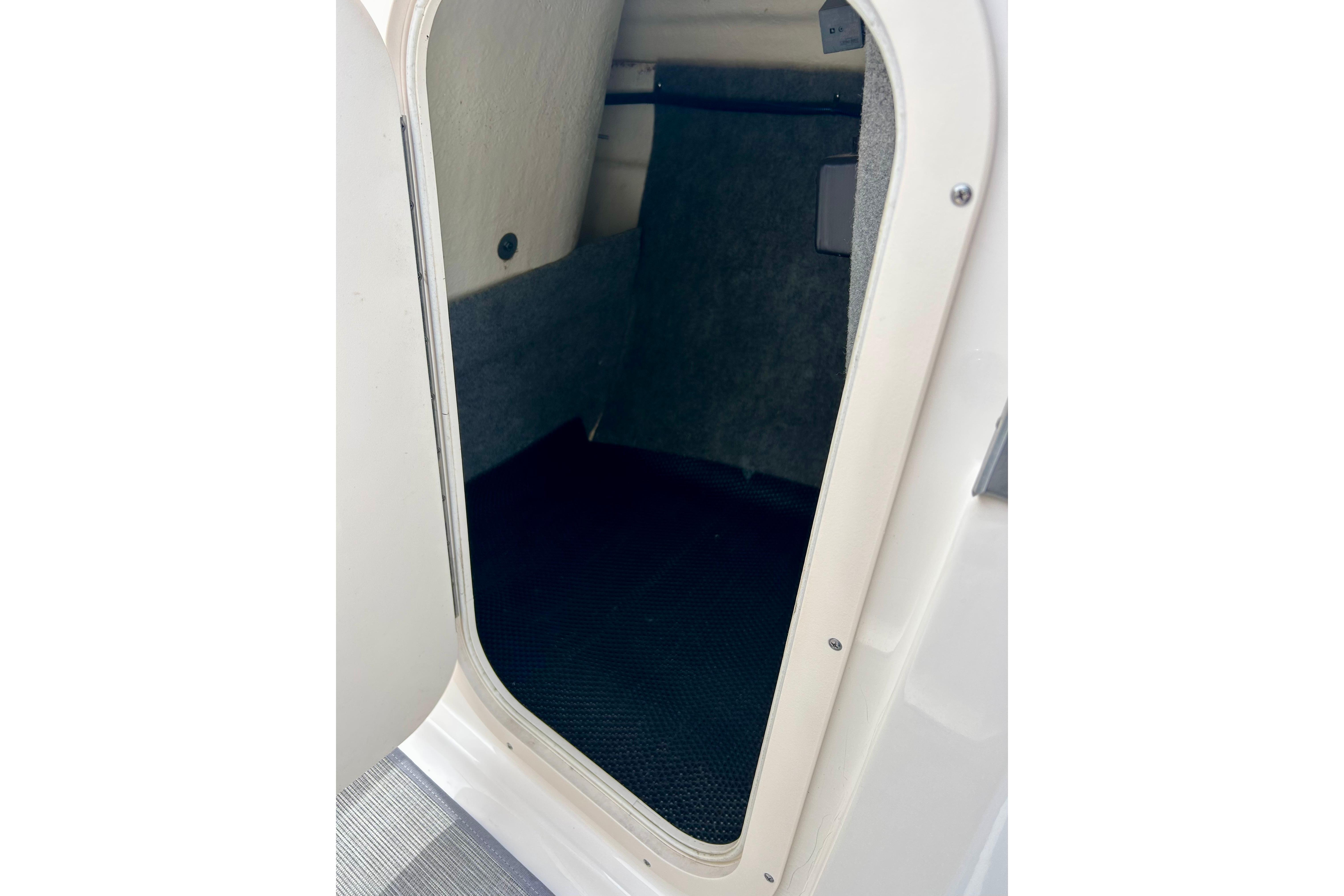 Storage compartment inside 2017 Chaparral 203 Vortex boat, featuring carpeted interior.