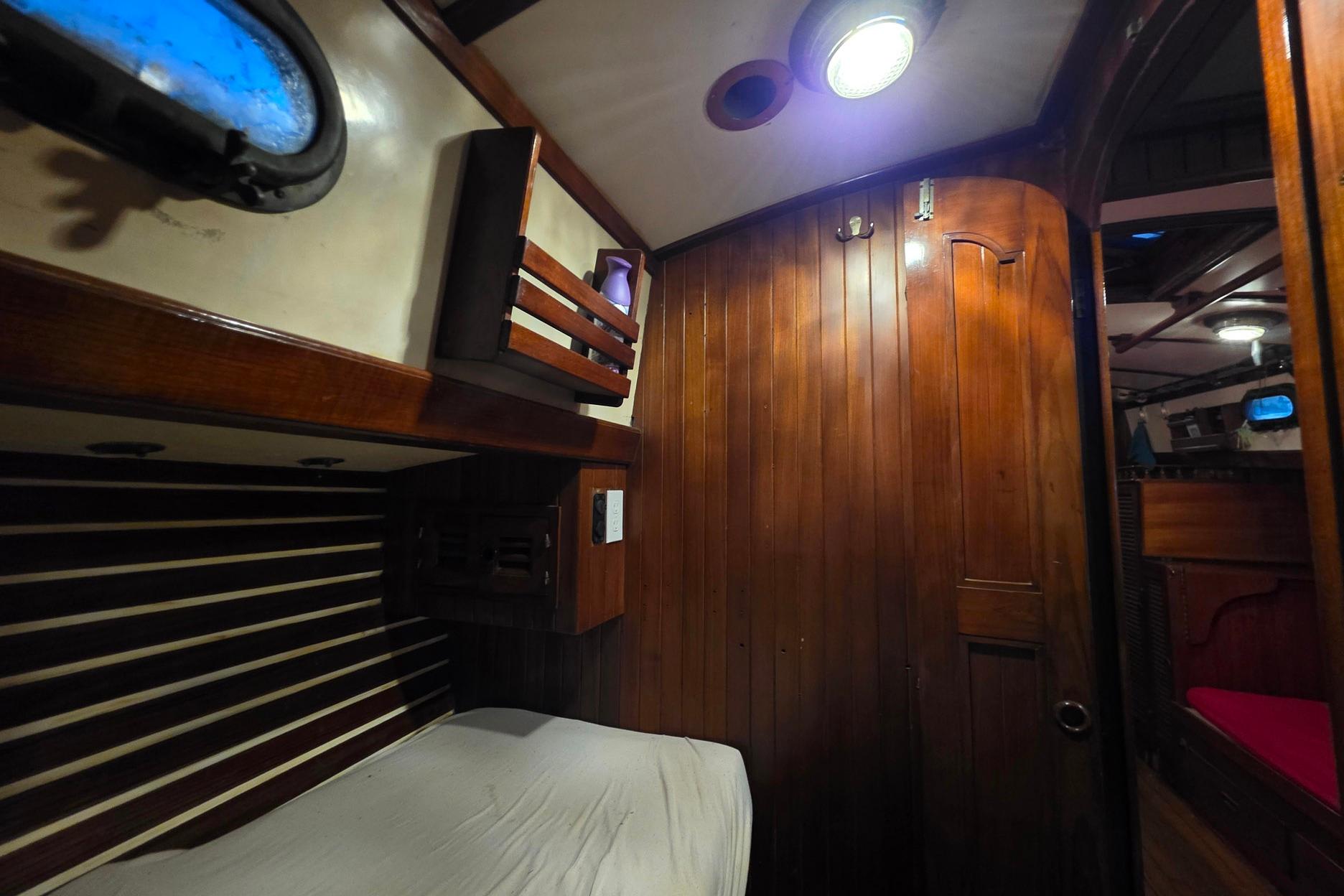 Cozy wooden interior of a 1982 Tayana 37 sailboat cabin with ambient lighting.