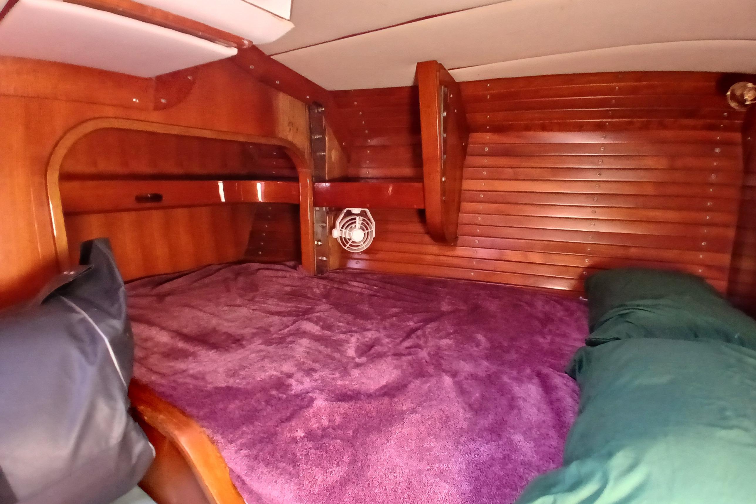 Cozy wooden cabin interior of 1981 SKYE 51 yacht with purple bedding.